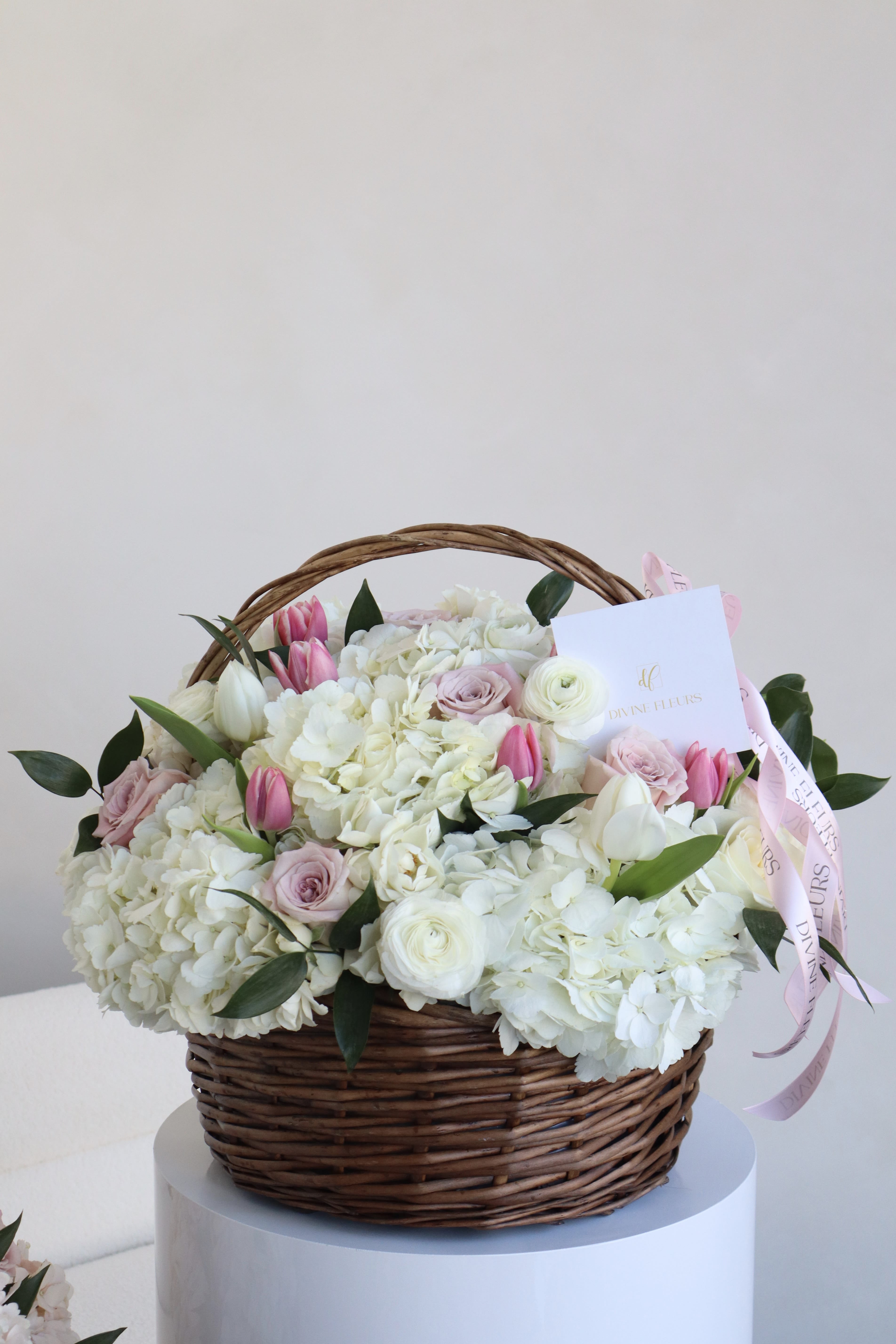 Basket of white and pink flowers with a ribbon and card