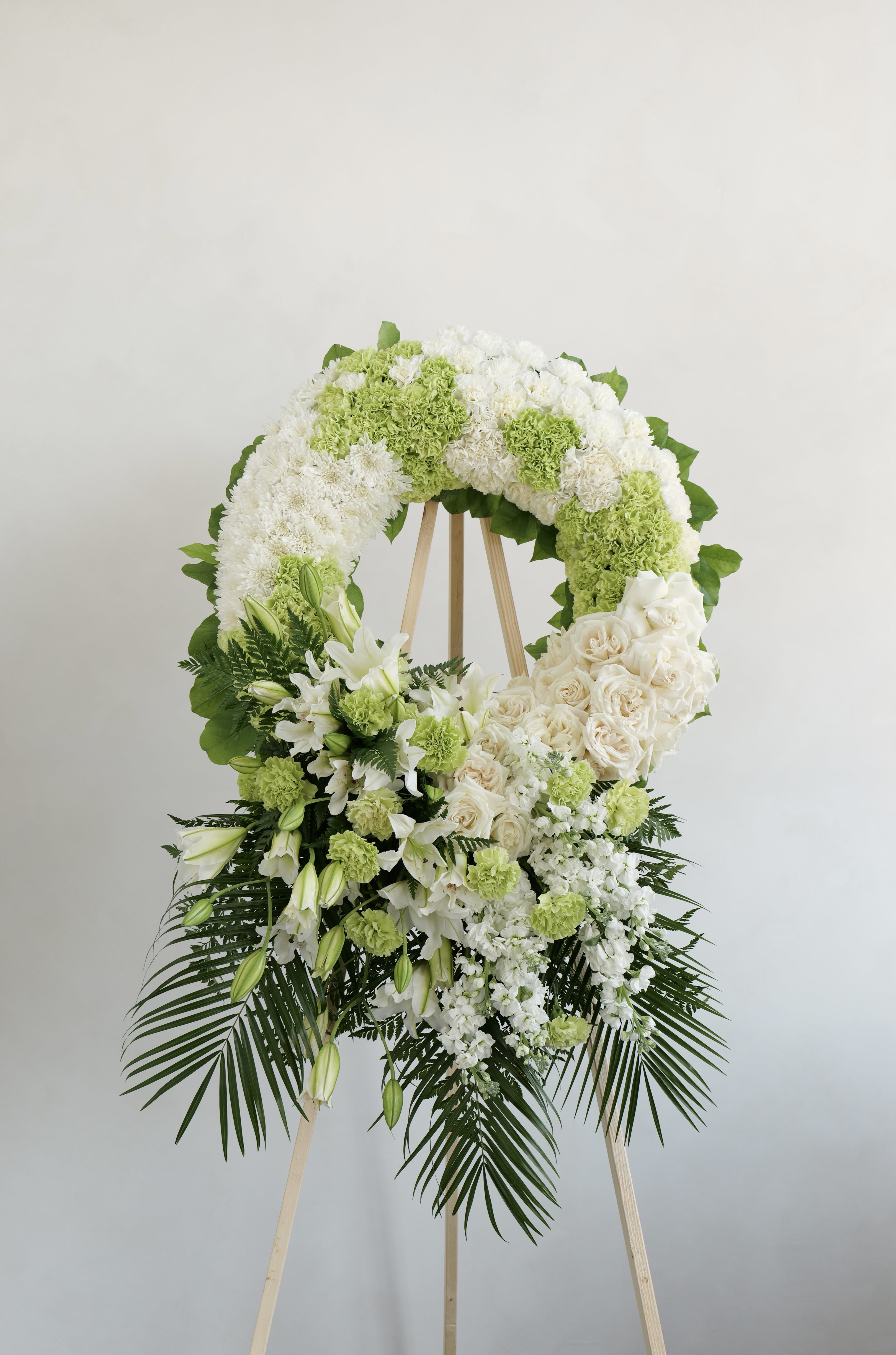 White and green funeral wreath on a wooden easel