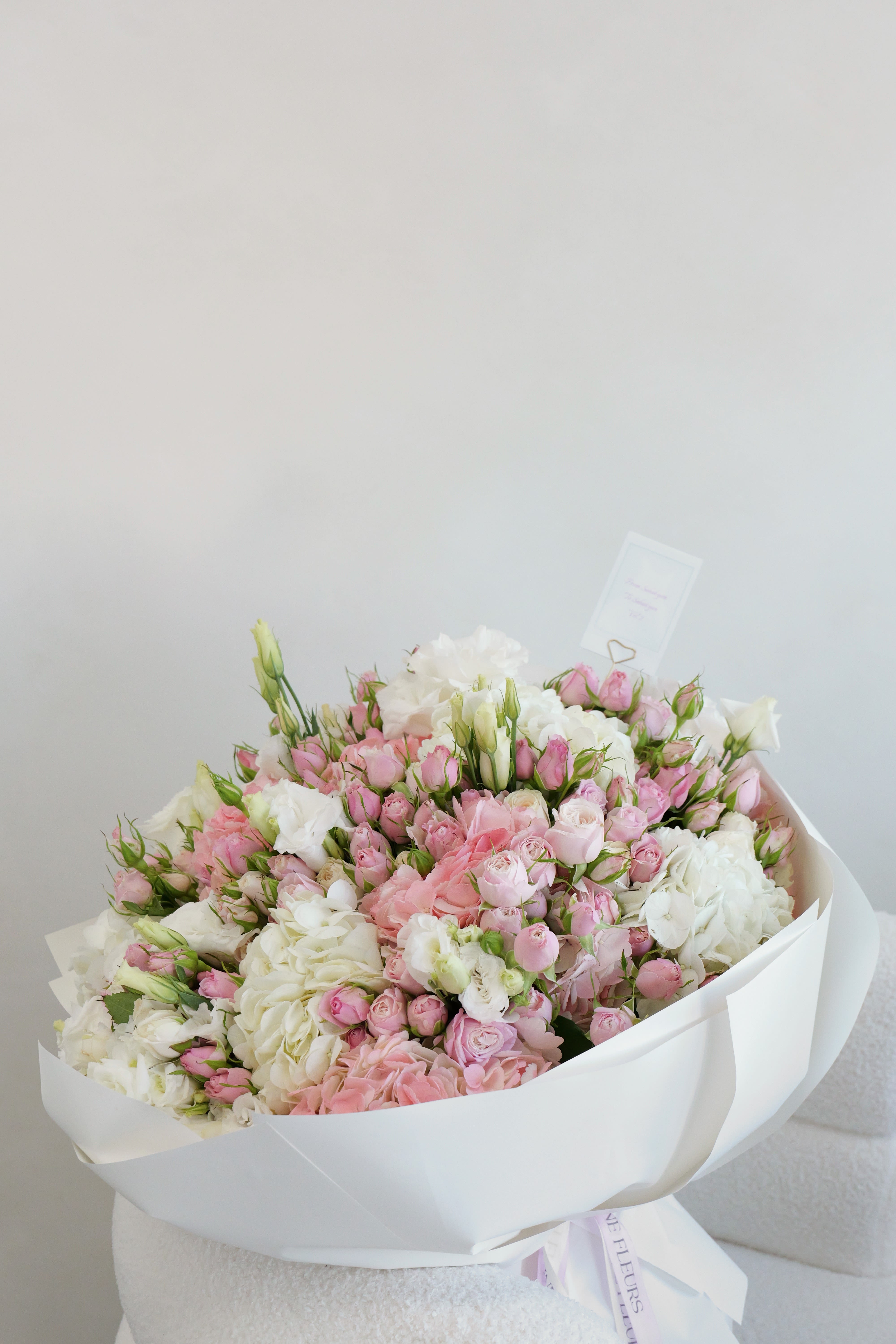 Large bouquet of pink and white roses wrapped in white paper