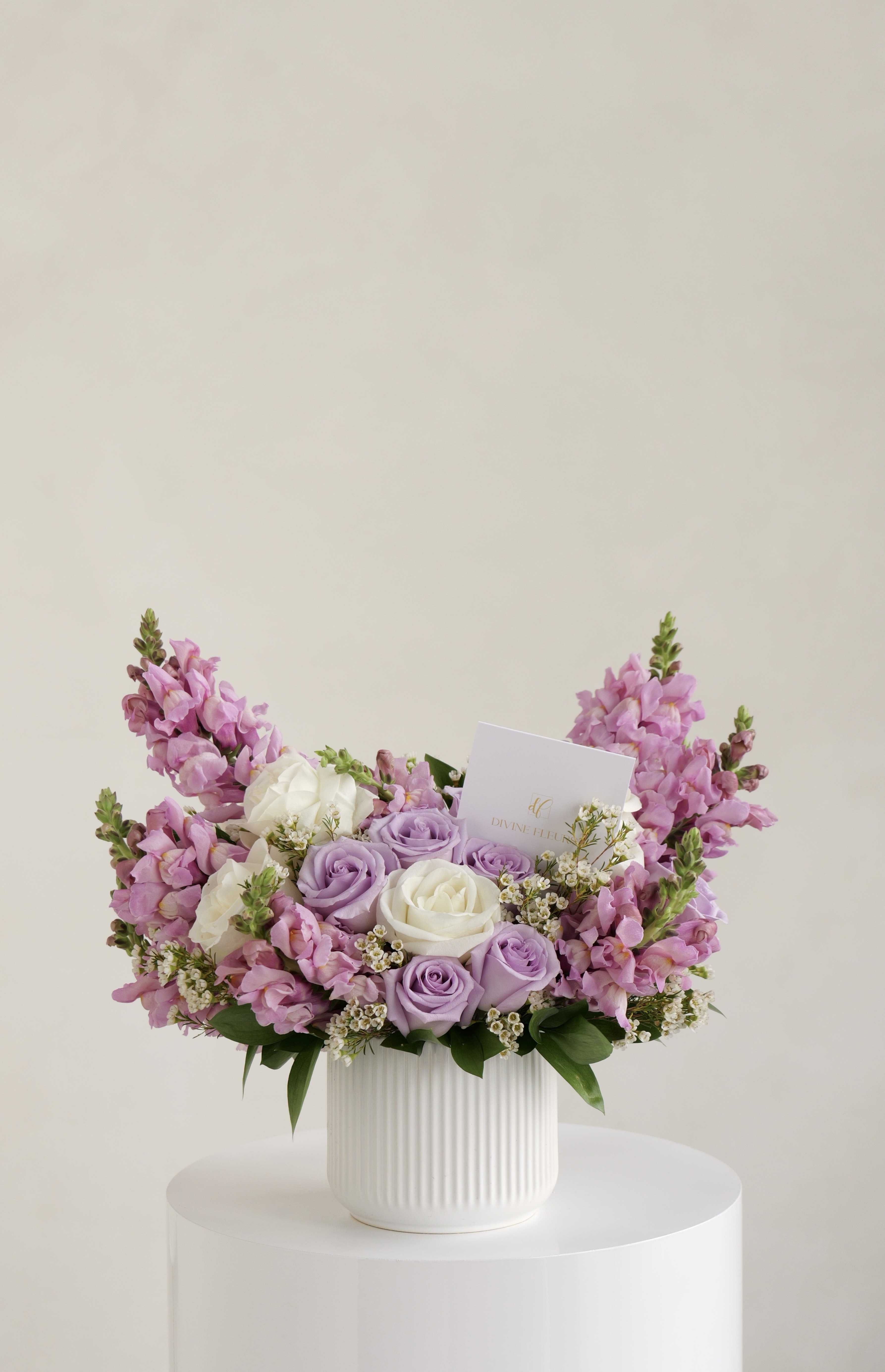 Pink and lavender roses arranged in a white ribbed vase