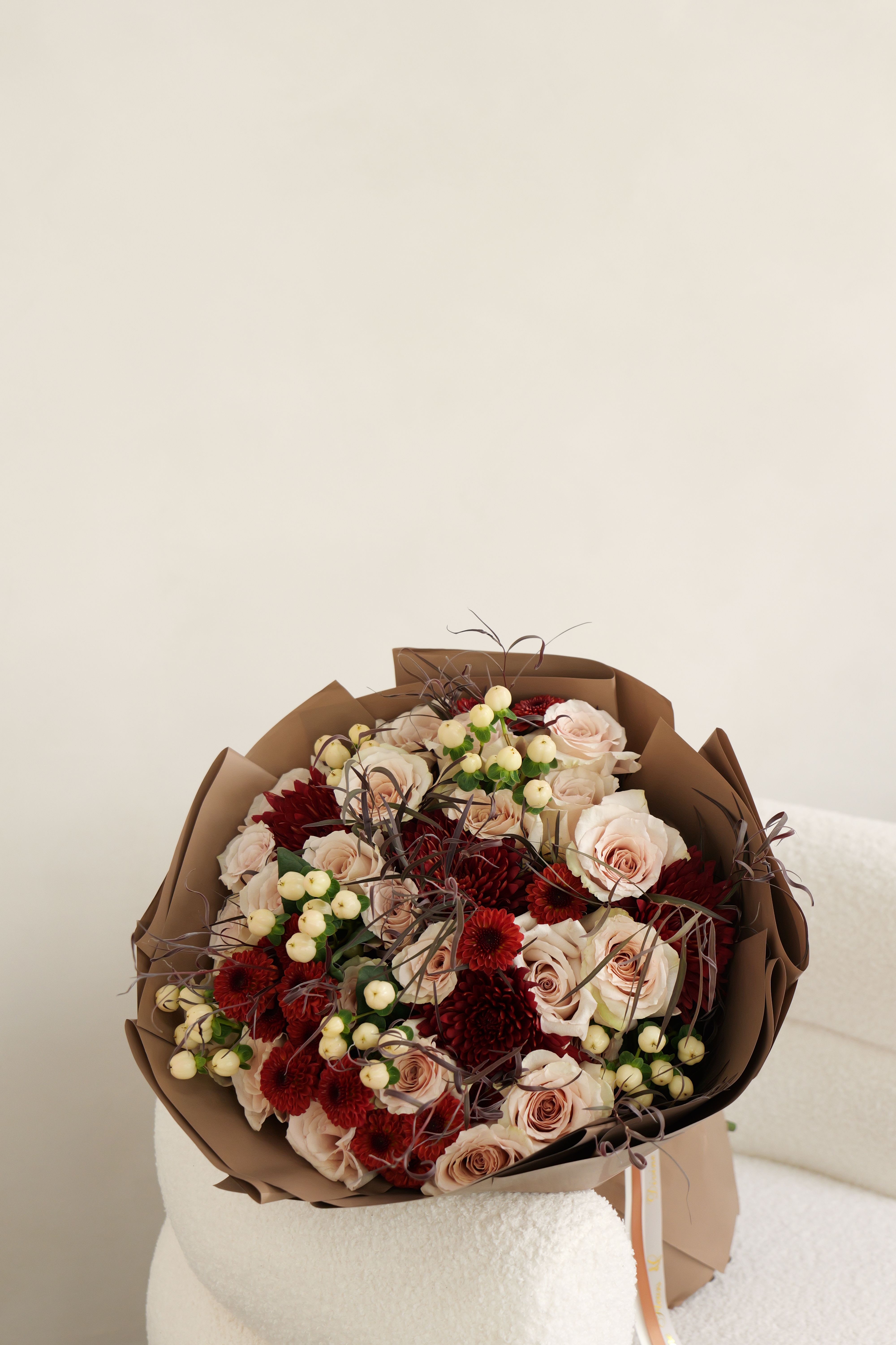 Bouquet of blush roses and red chrysanthemums wrapped in brown paper