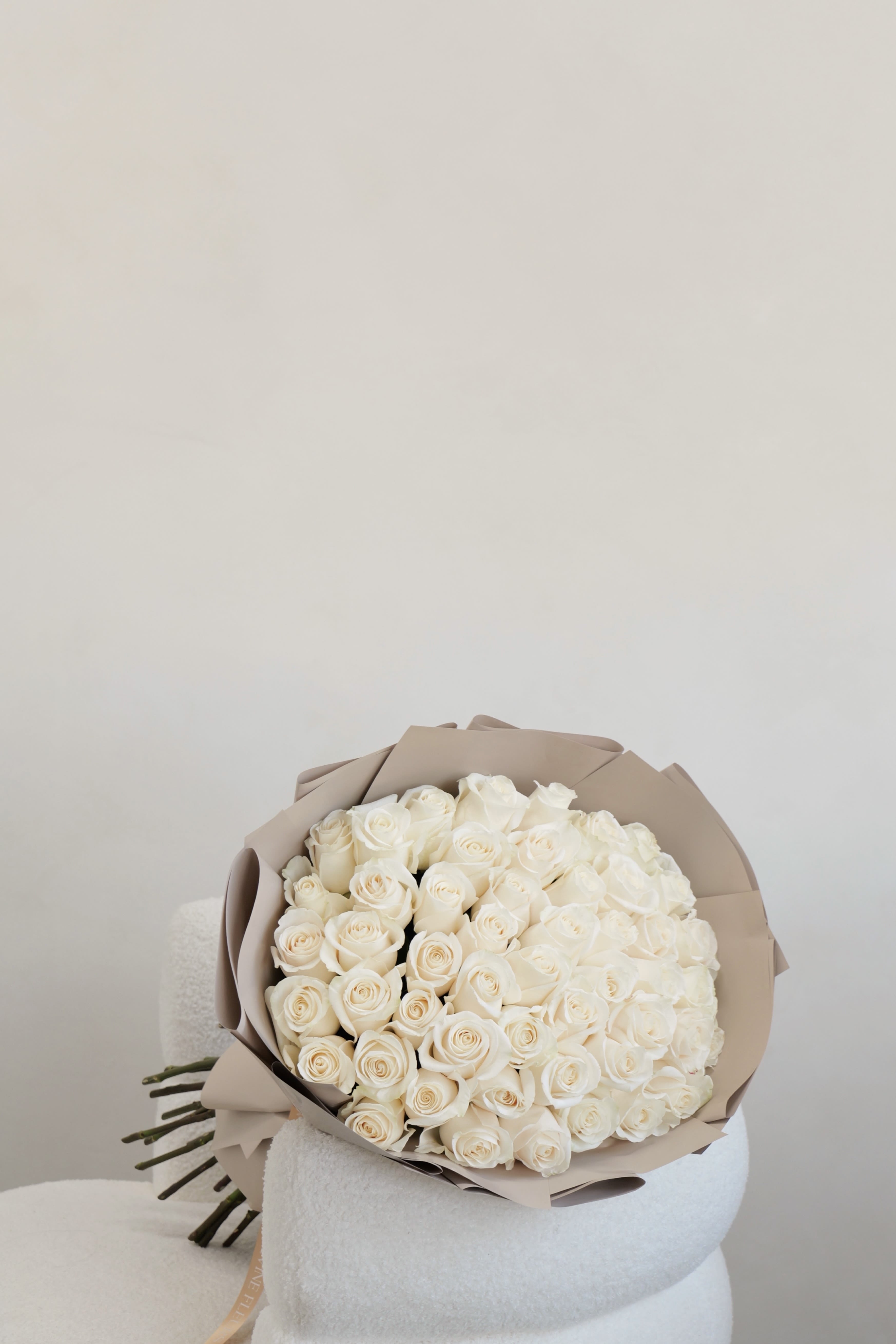 Bouquet of white roses wrapped in beige paper