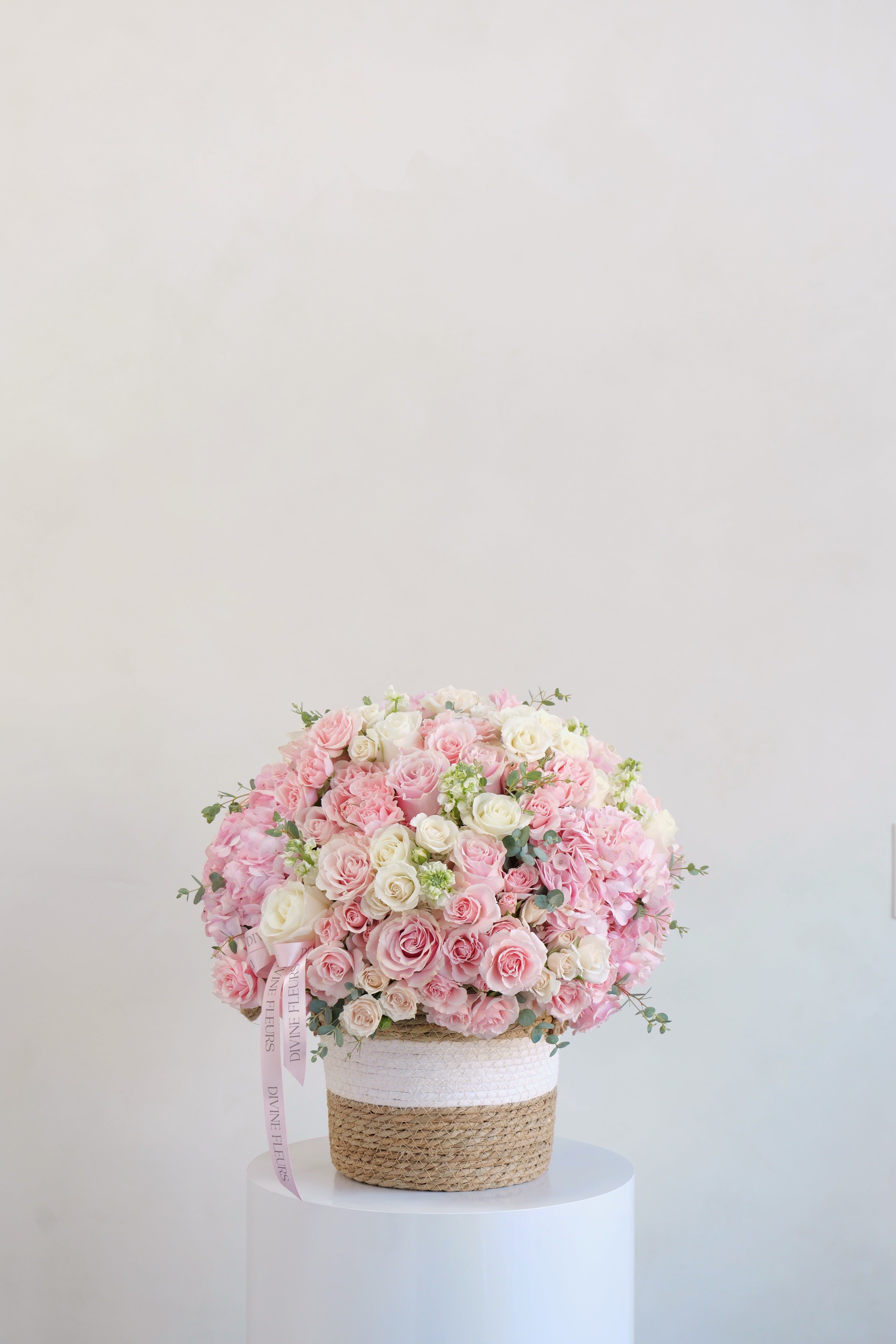 Large pink and white rose arrangement in a woven basket