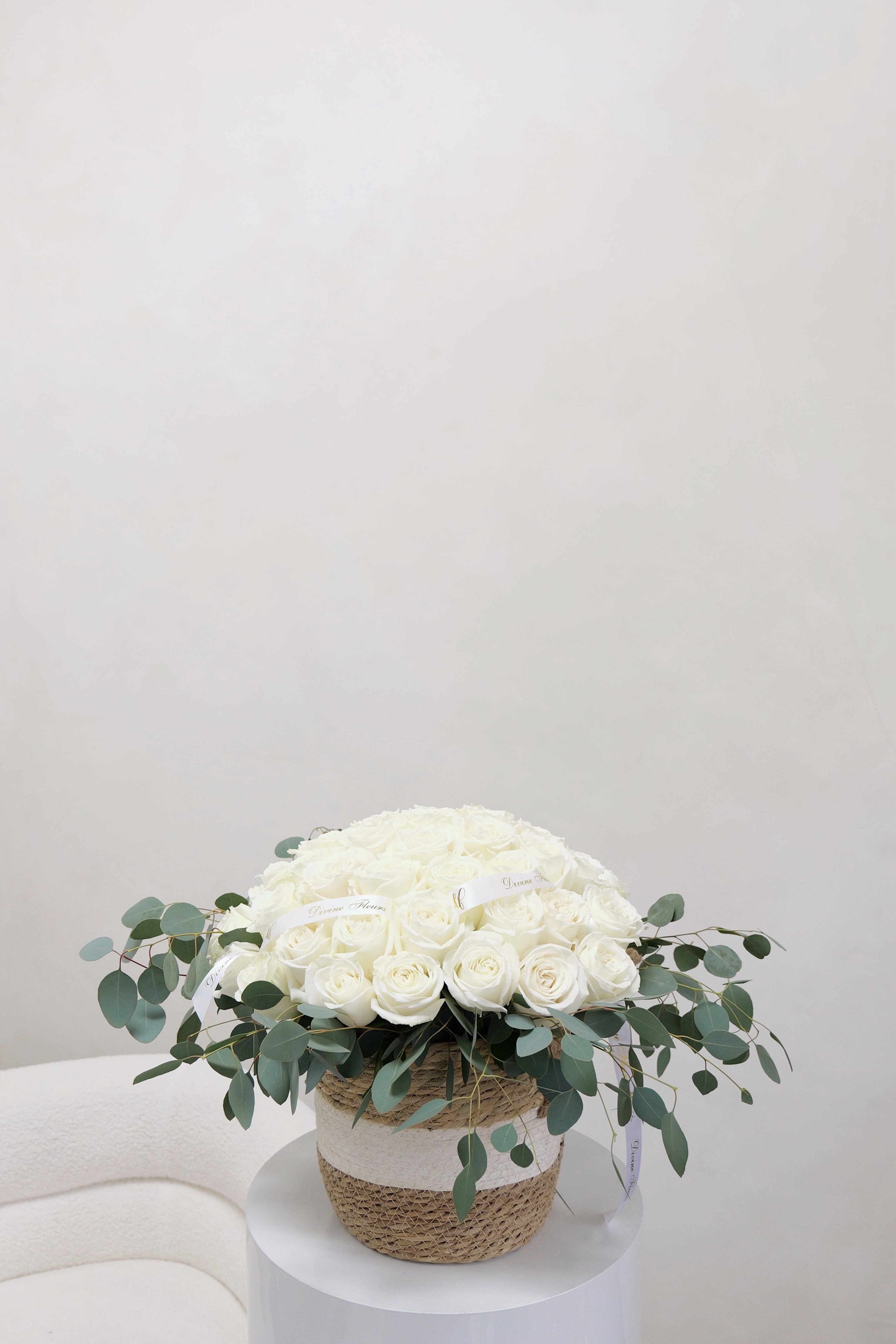 White rose arrangement in a woven basket with eucalyptus