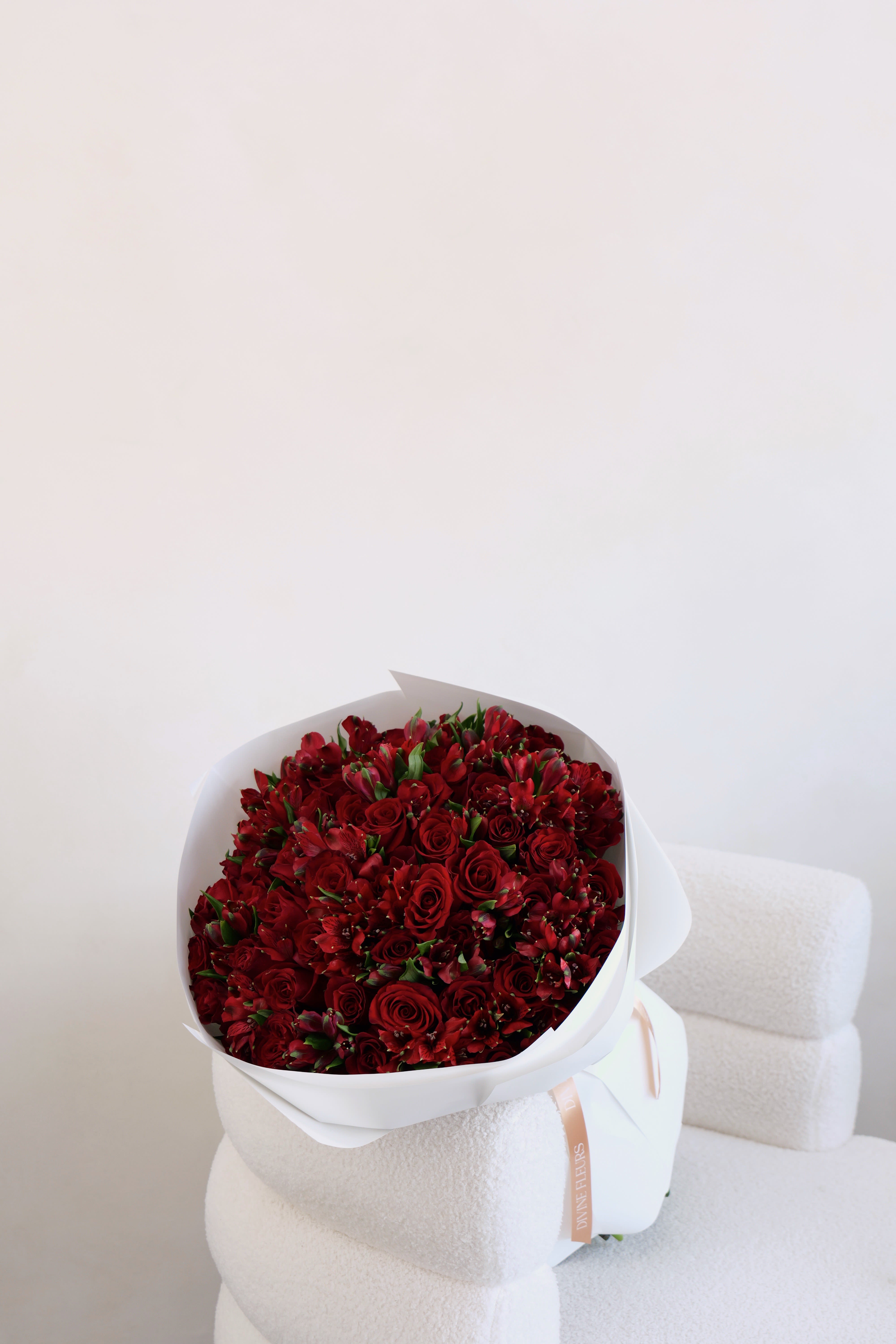 Bouquet of red roses and red alstroemeria wrapped in white paper