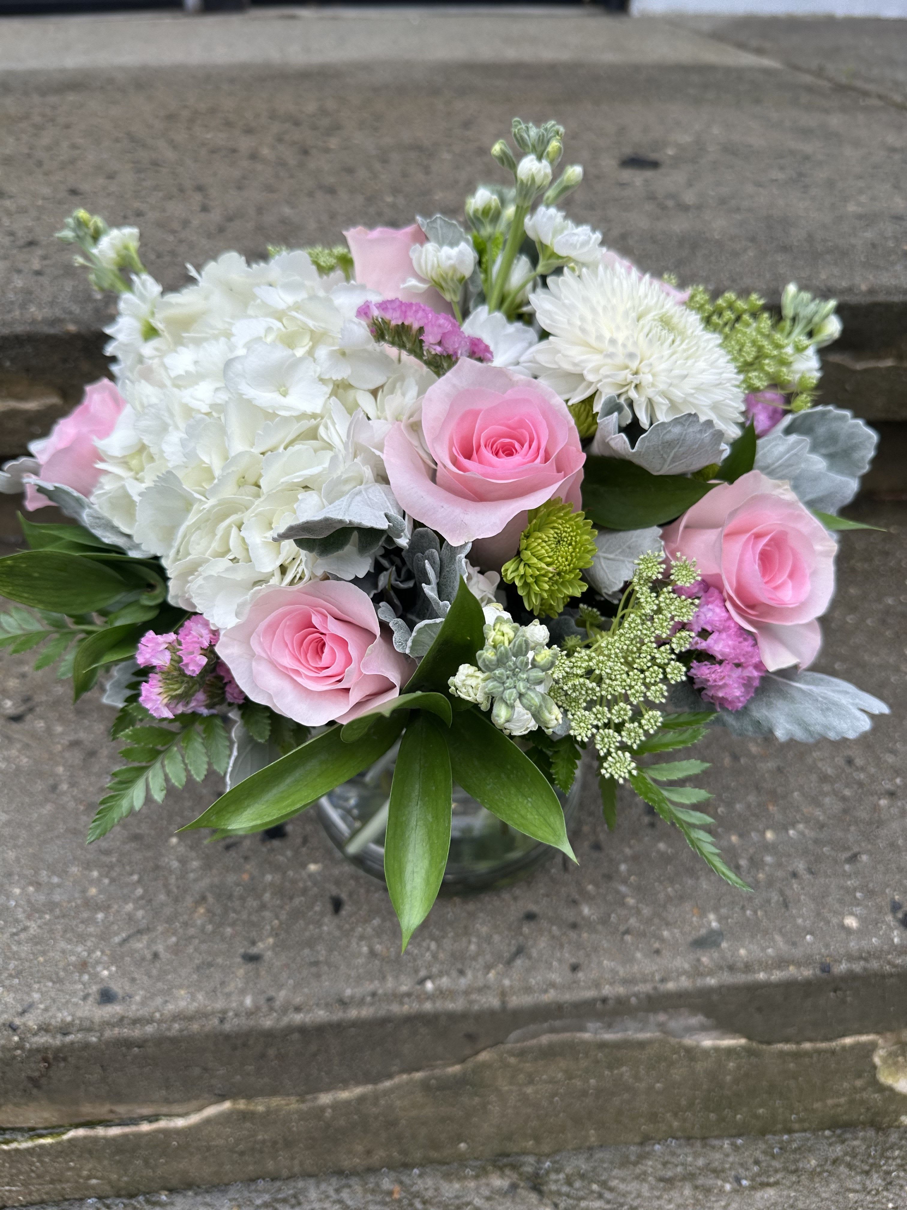 Pink roses and white flowers arranged in a glass vase