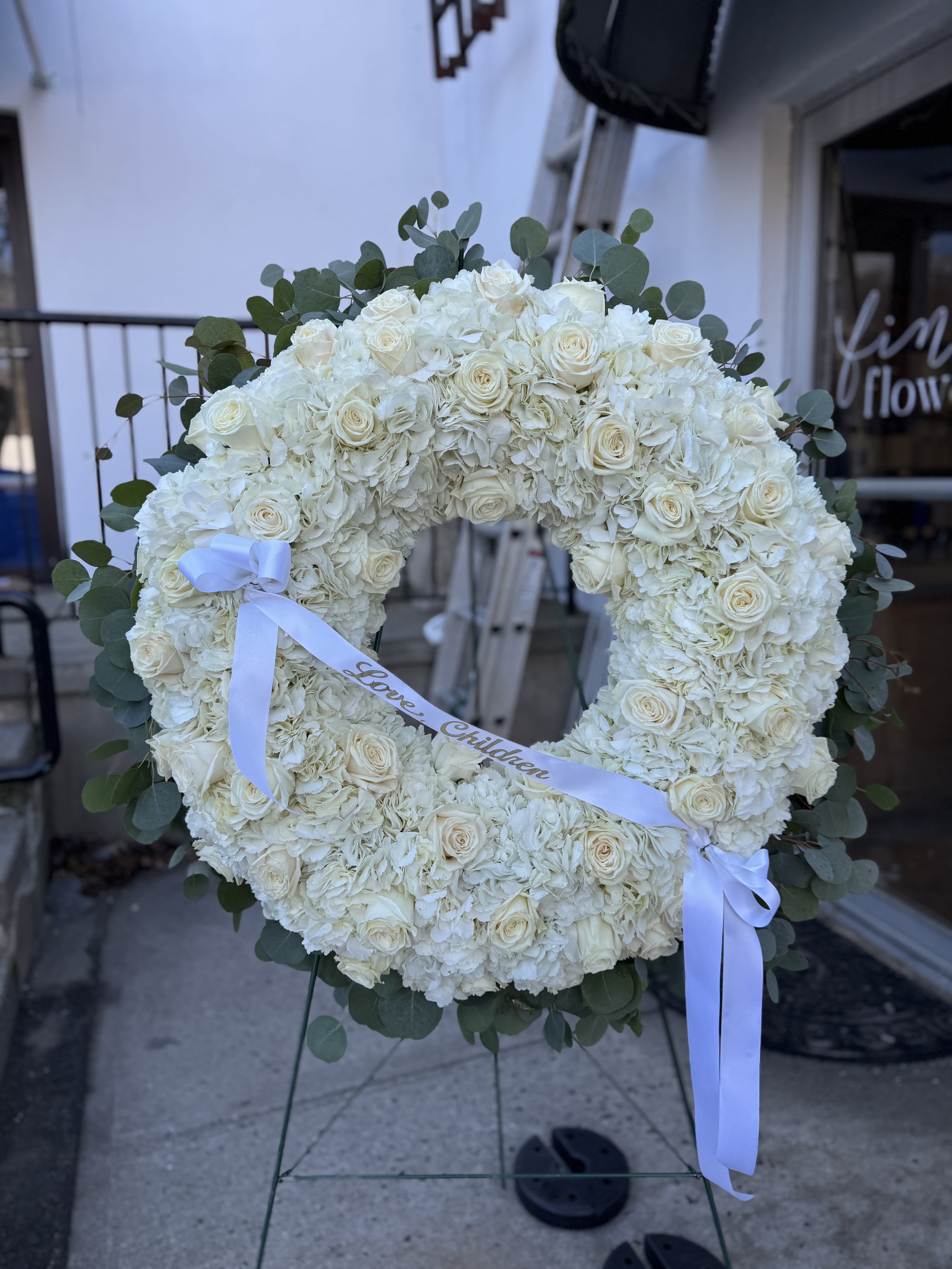 White floral wreath on an easel with a ribbon