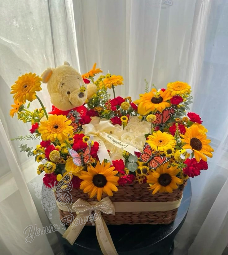 Basket arrangement of sunflowers, red flowers, and a teddy bear