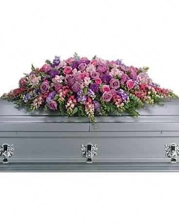 Pink and purple floral casket spray on a gray casket