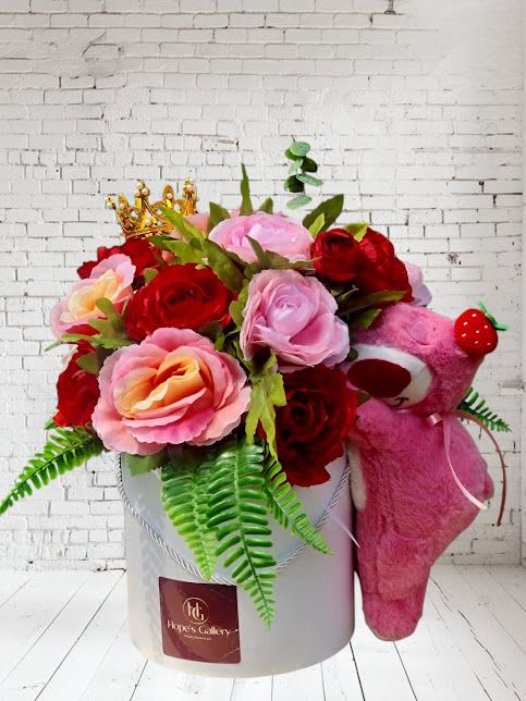Pink and red rose arrangement in a white box with a pink teddy bear