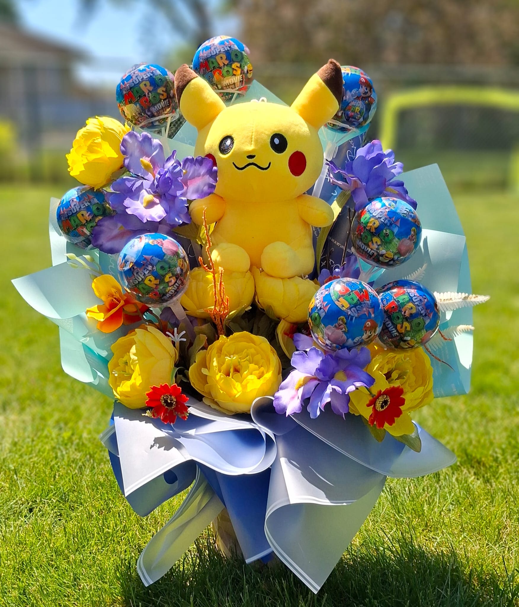 The Pikachu &amp; Friends Gamer Bouquet - The ultimate gift designed to bring their favorite games to life! This spectacular, everlasting bouquet features a soft, high-quality Pikachu plush center, surrounded by vibrant silk blossoms and fun Super Mario Bros. Movie lollipops. Artfully wrapped in modern Korean style paper, it is a joyful, zero-maintenance gift. Once the treats are enjoyed, this beautiful keepsake stays perfect forever, making it a vibrant and playful addition to decorate any child's bedroom or gaming space."