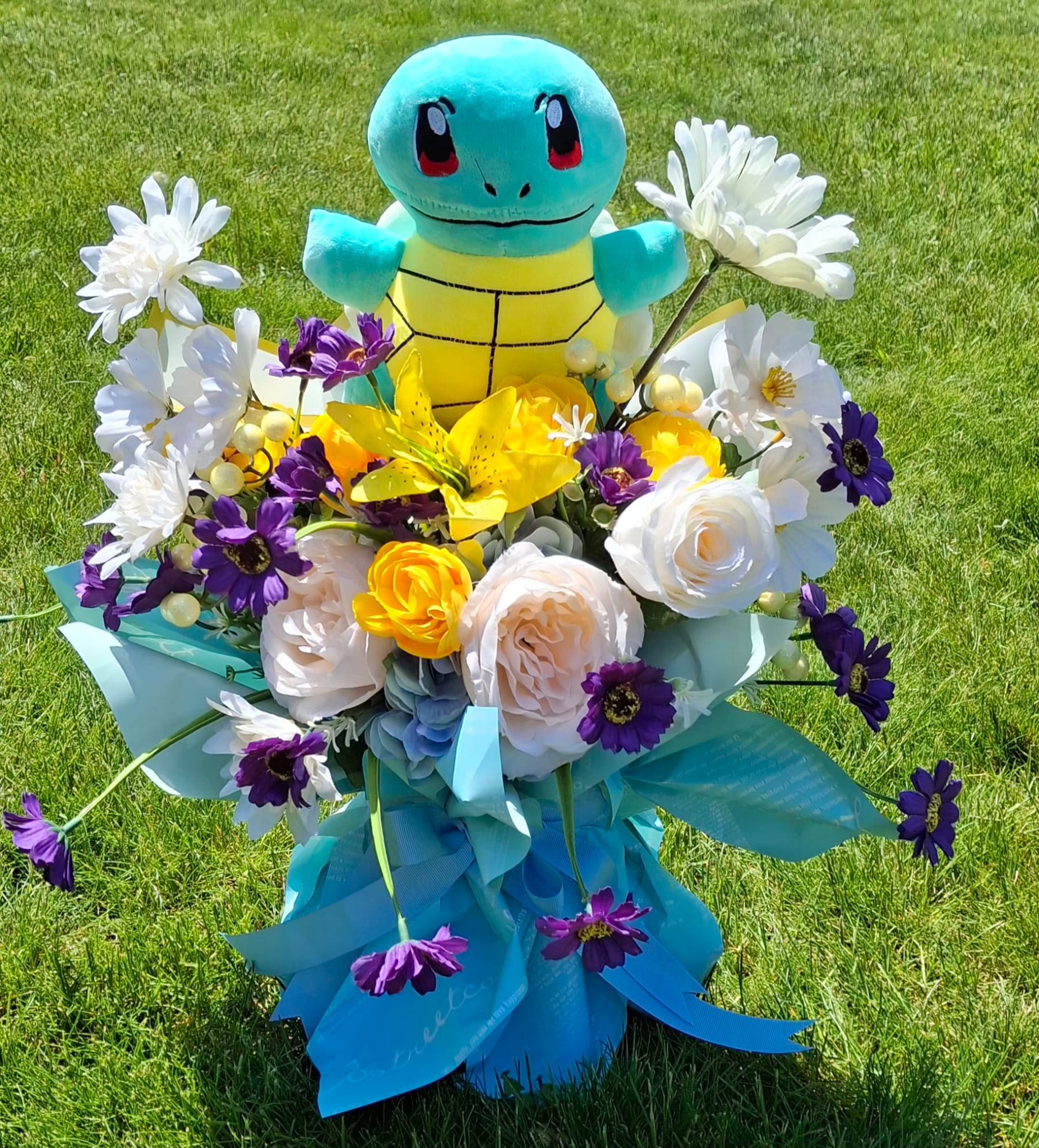Squirtle Splash Bouquet - "Bring a wave of joy to their special day with the ultimate Pokémon surprise! This spectacular, everlasting bouquet features a soft, high-quality Squirtle plush nestled in a vibrant, whimsical garden of premium silk yellow lilies, white garden roses, and playful purple daisies. Artfully wrapped in modern blue and aqua Korean-style paper, this beautiful keepsake bouquet requires zero maintenance. Once received, it transforms into a lovely plush toy and a colorful, fun decor piece to brighten any child's bedroom."