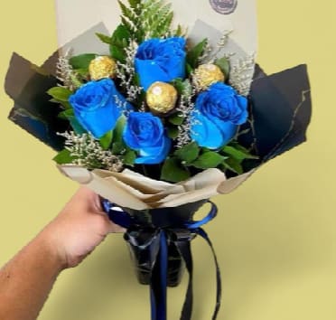 Sapphire &amp; Gold Distinction - The perfect gift for the man you admire. An imposing hand-tied bouquet featuring deep sapphire blue roses, elegantly paired with premium Ferrero Rocher chocolates and select greenery. Beautifully wrapped in high-quality black and cream paper layers with a satin bow.