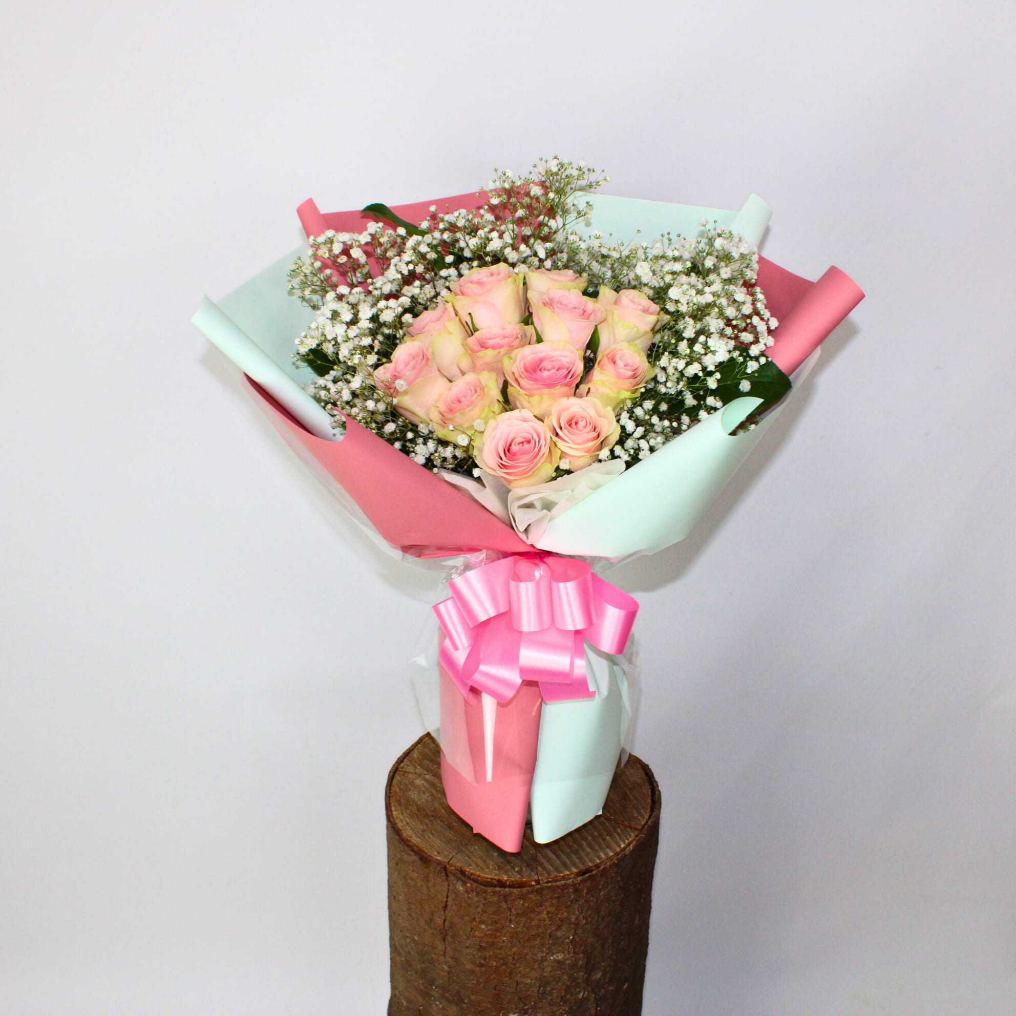 Bouquet of pink roses with baby's breath wrapped in pastel paper