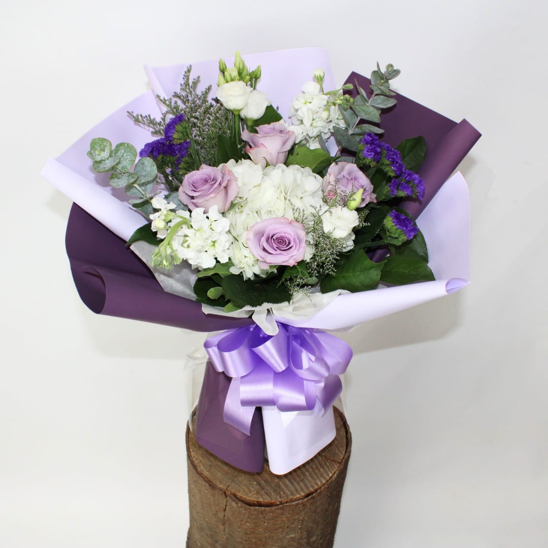 Bouquet of lavender and white flowers wrapped in purple paper