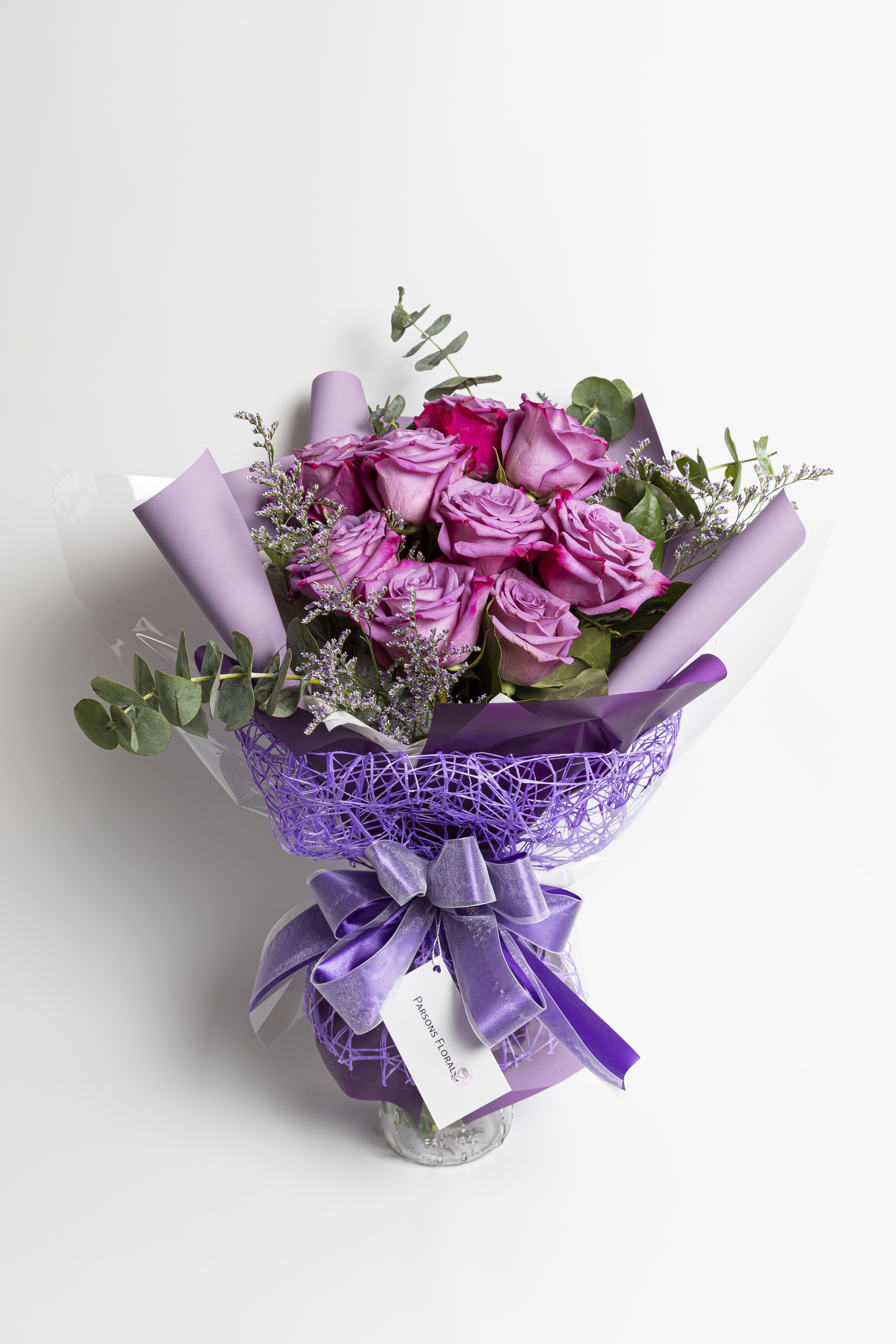 Bouquet of lavender roses wrapped in purple paper with a ribbon