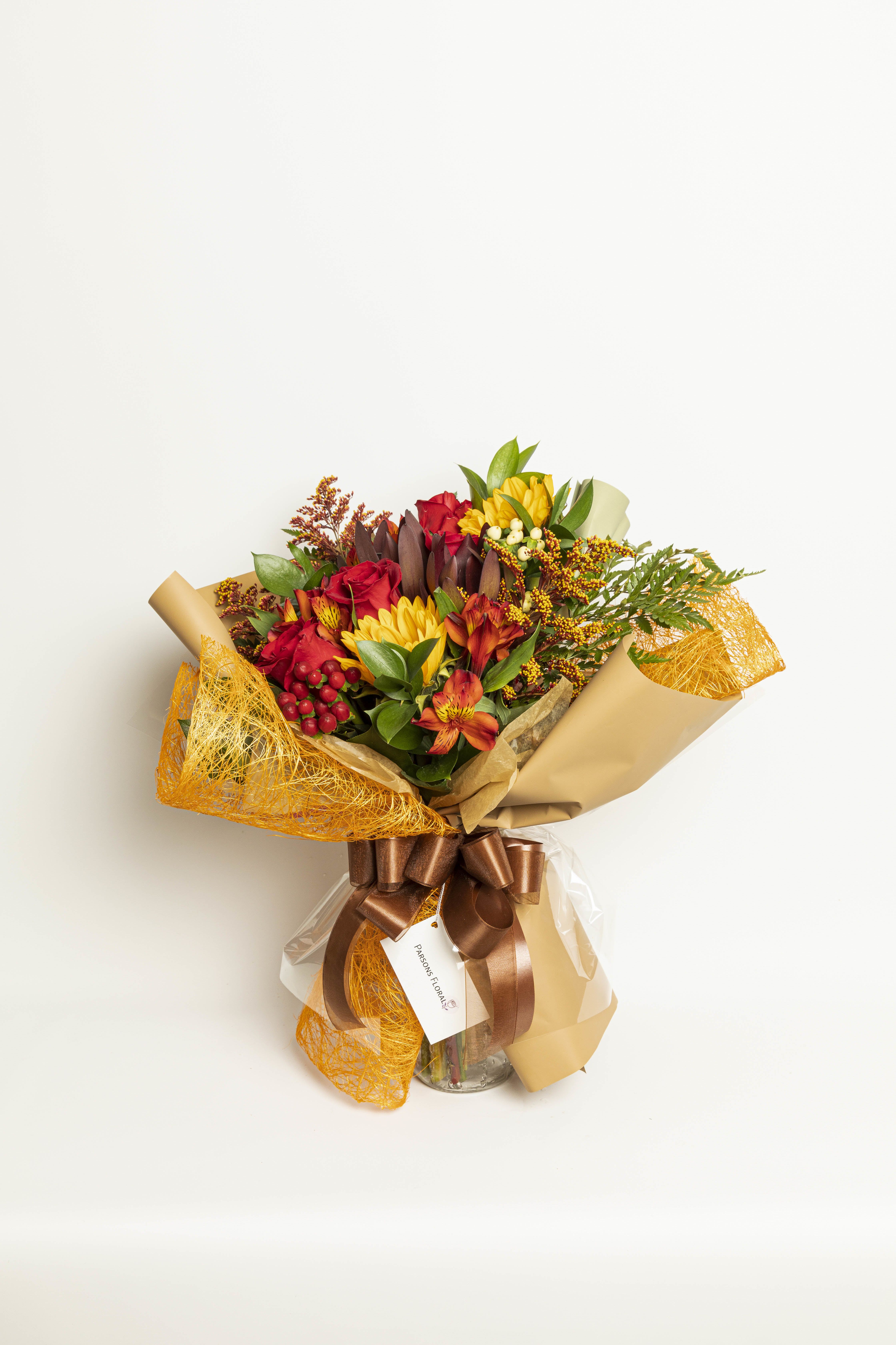 Bouquet of red roses and yellow flowers wrapped in tan paper