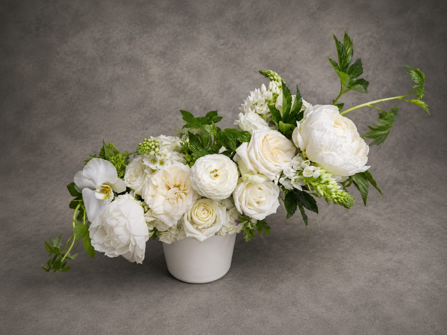 Claire - Claire features an artful collection of premium white blooms, including peonies, garden roses, orchids, and seasonal florals. Soft textures and sculptural movement create a refined composition that feels both timeless and effortlessly sophisticated.