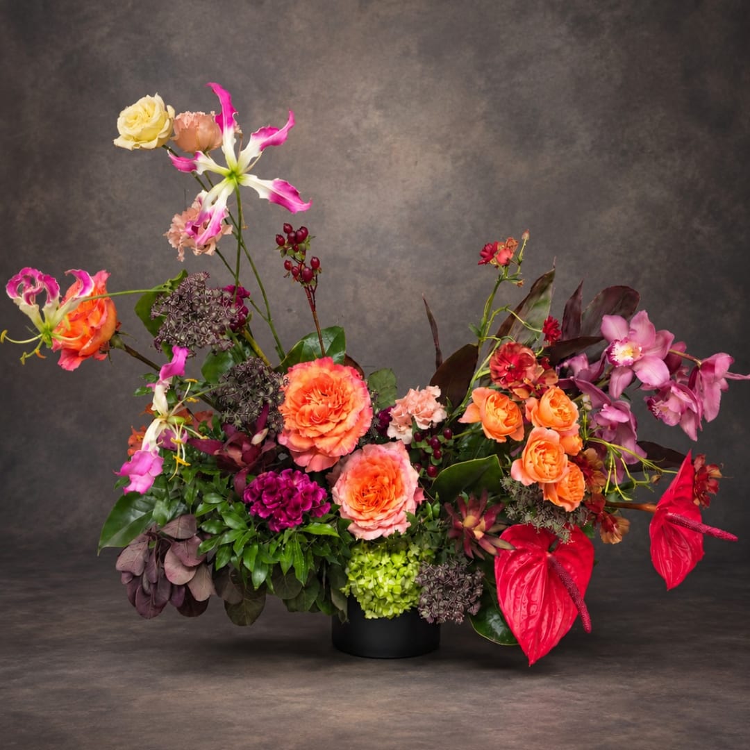 Colorful floral arrangement in a black vase with orange, pink, and purple blooms