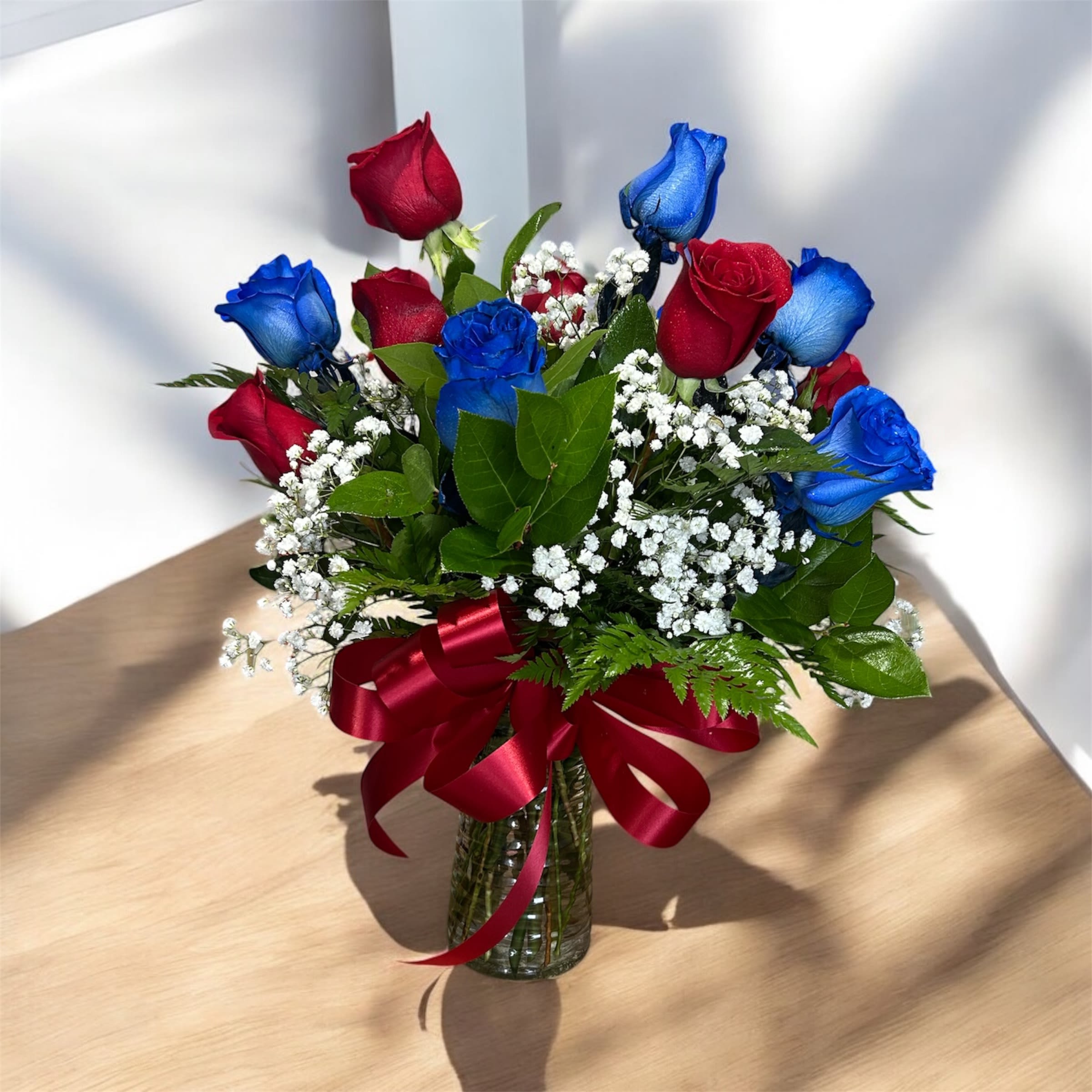 Bouquet of red and blue roses in a glass vase with a red ribbon