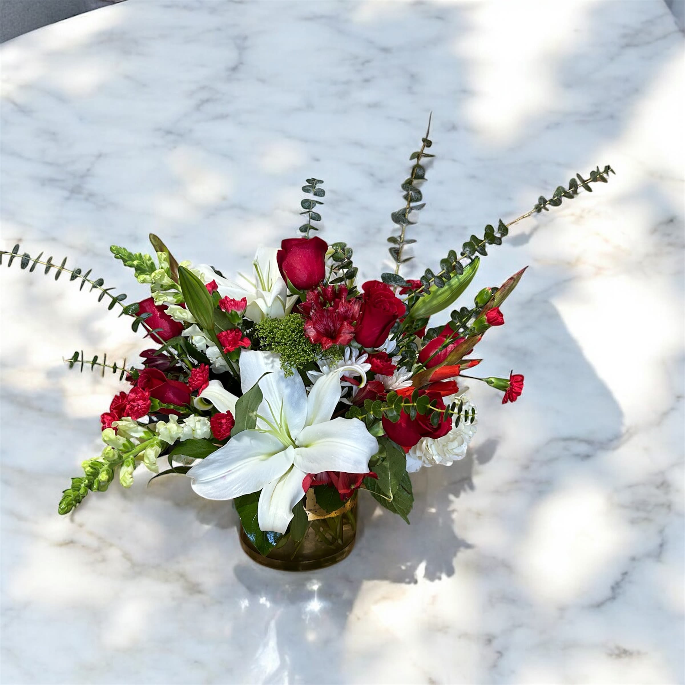 Red and white floral arrangement in a glass vase