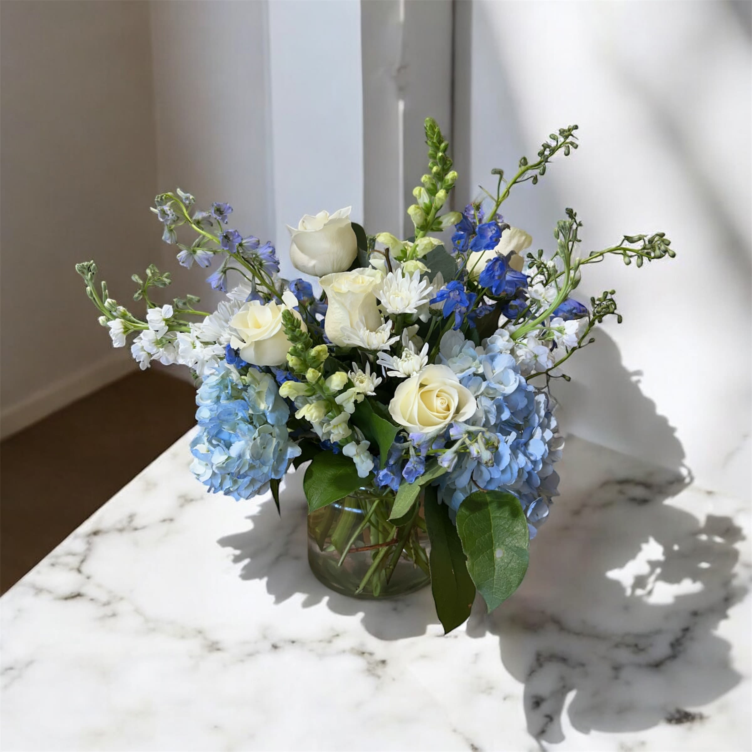 Blue and white flower arrangement in a glass vase