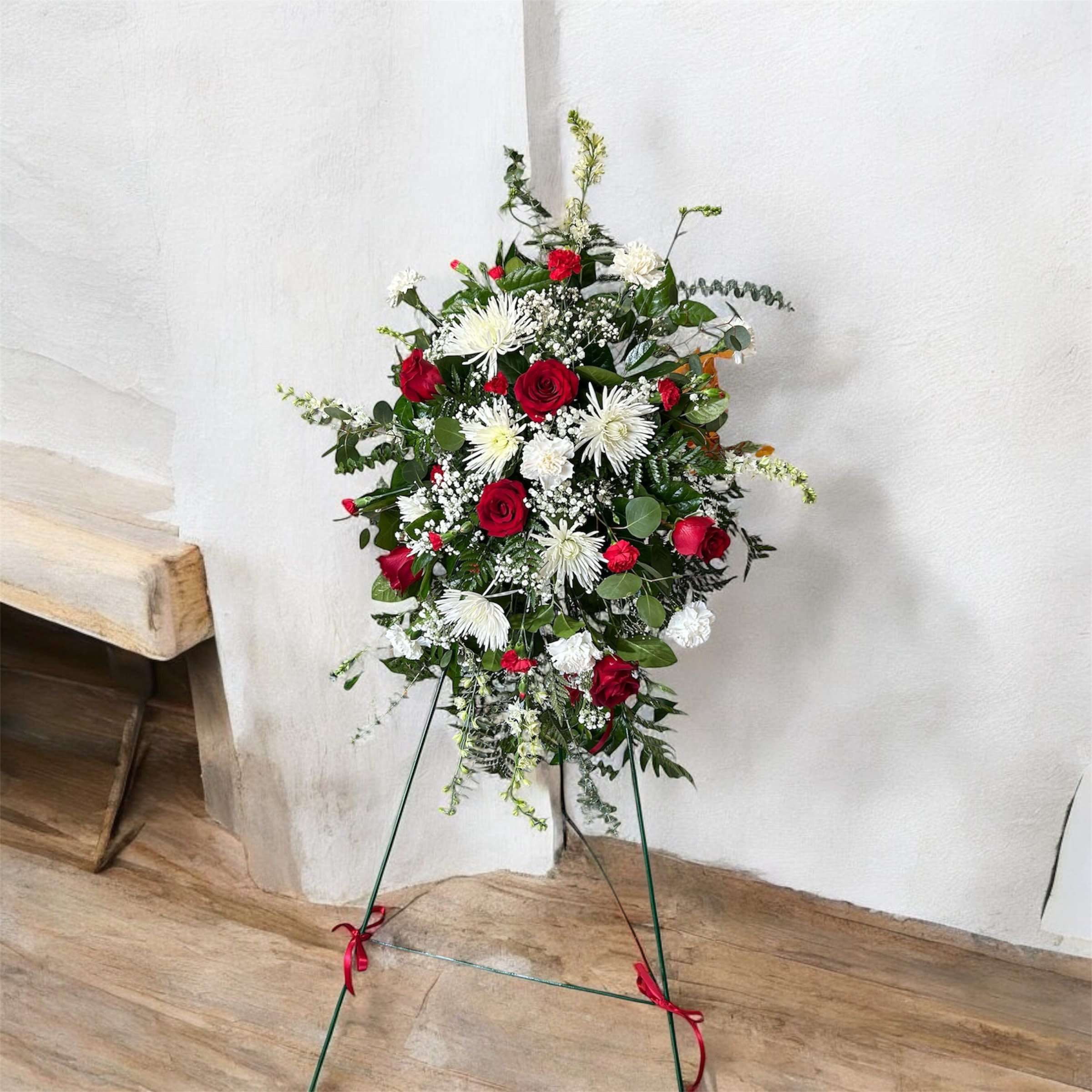Standing floral spray with red roses and white blooms on a metal easel