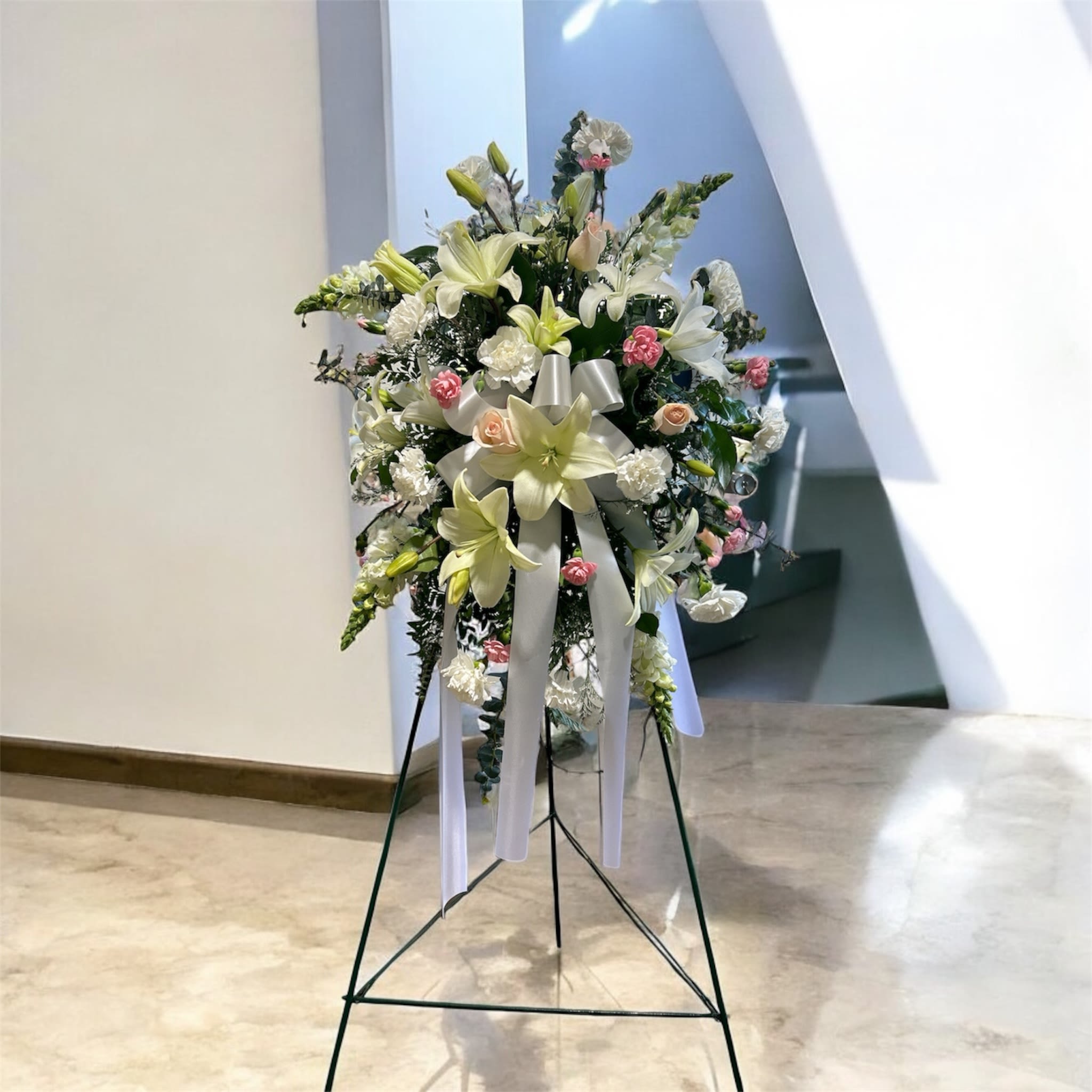 Standing floral spray with white lilies and pink carnations on an easel