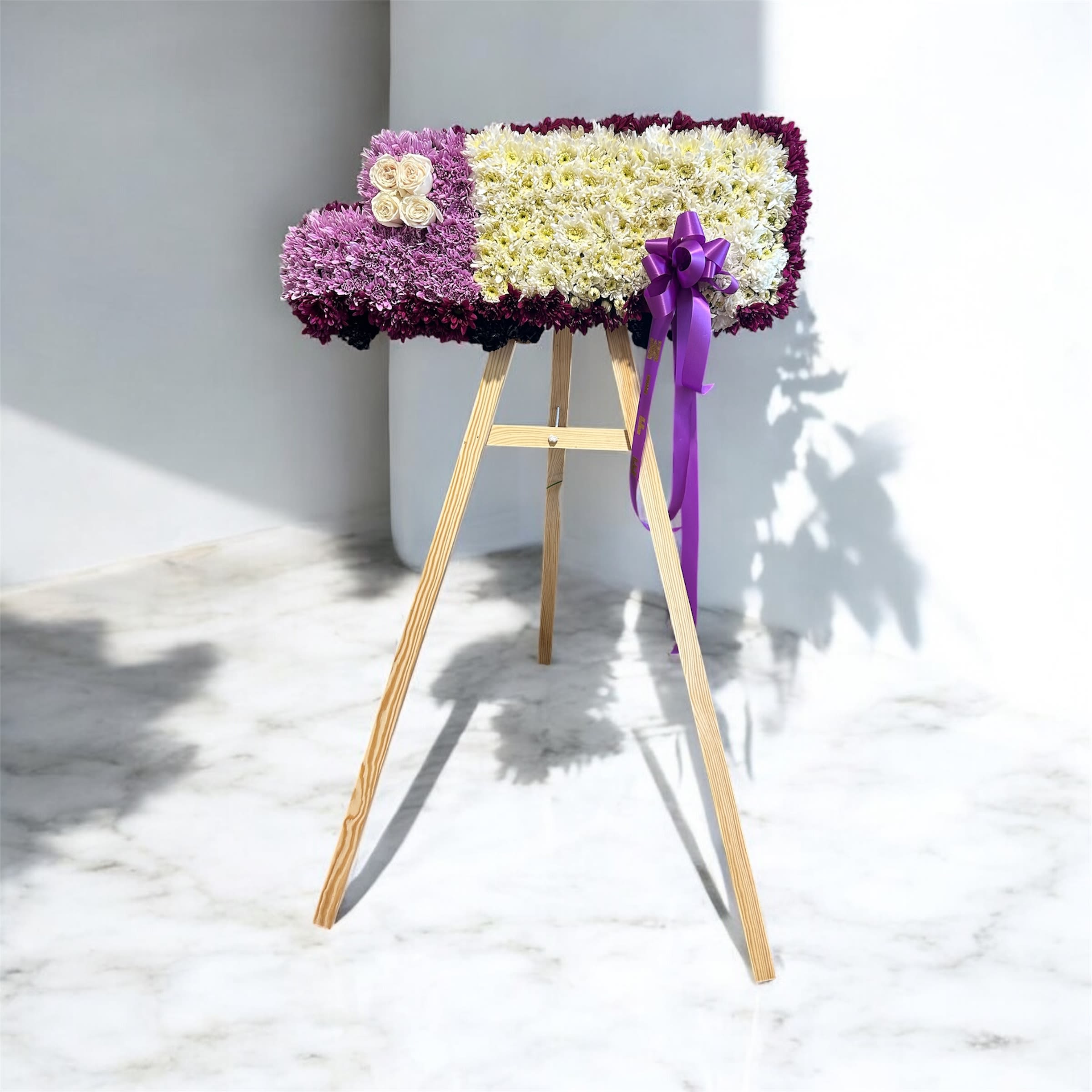Rectangular floral standing spray on a wooden easel with purple ribbon