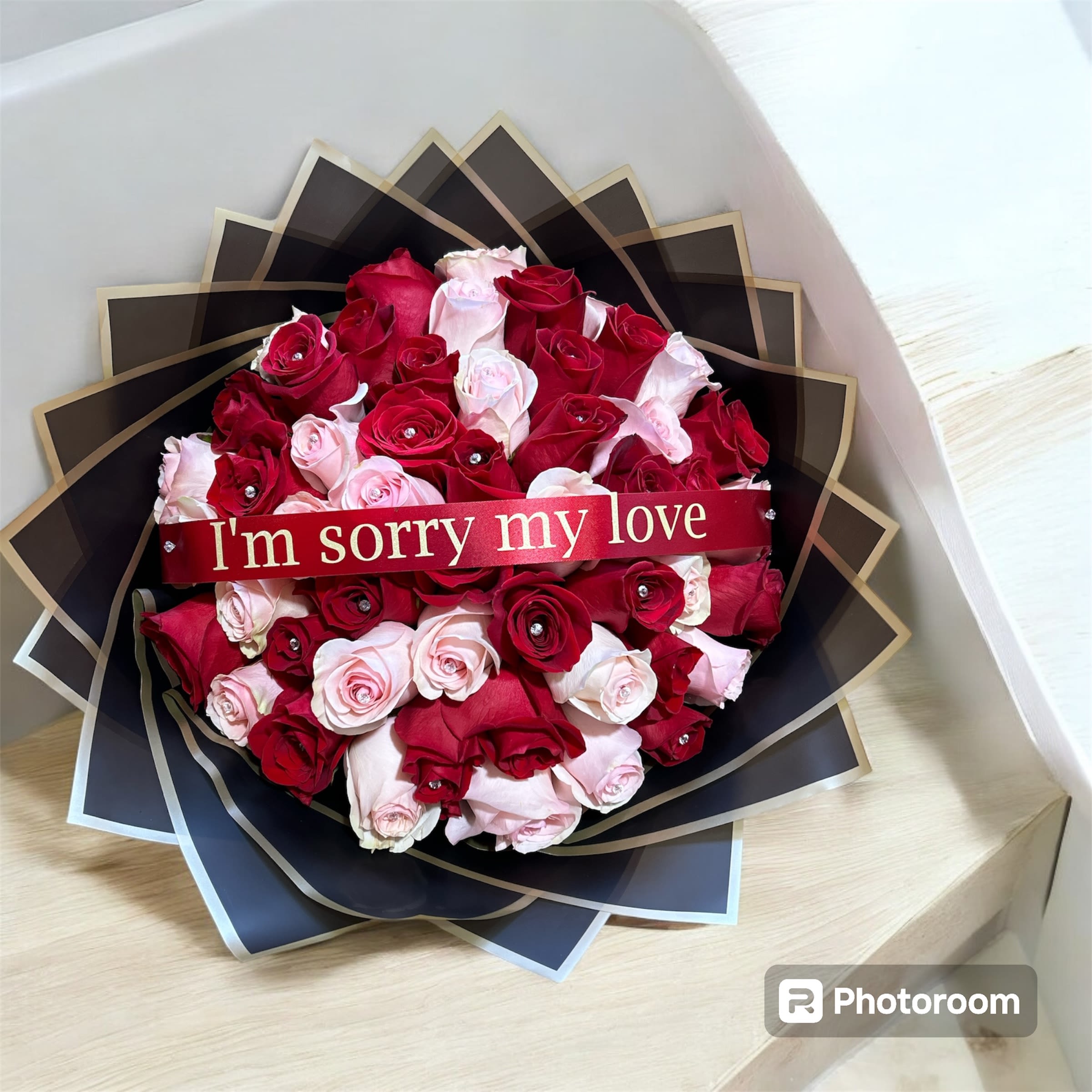 Bouquet of red and pale pink roses with a ribbon reading "I'm sorry my love"