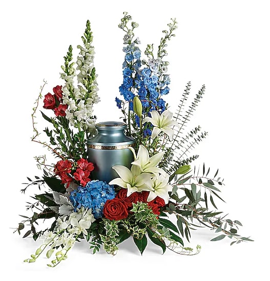 Sympathy arrangement with red, white, and blue flowers around a blue urn