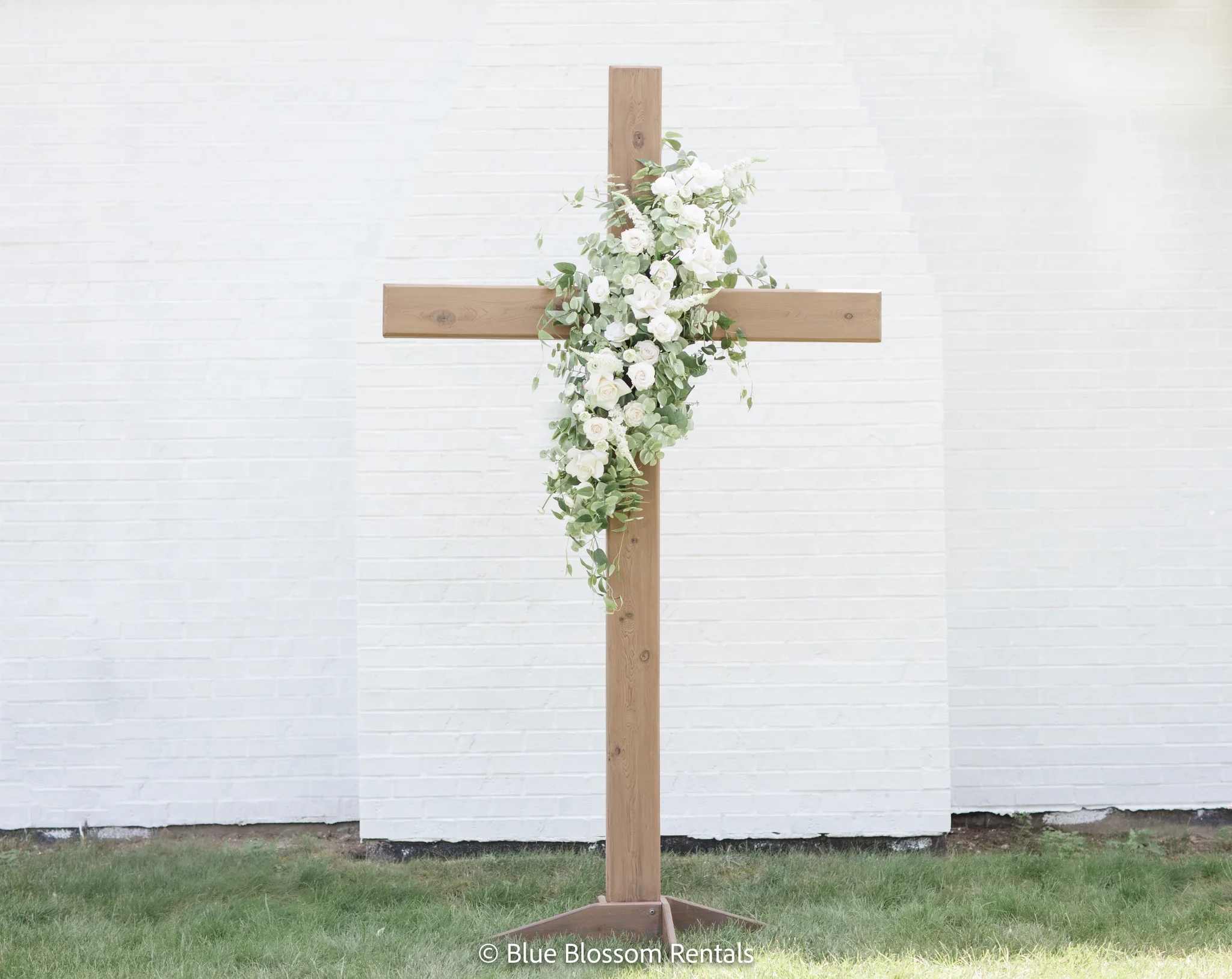 White floral arrangement on a wooden cross stand