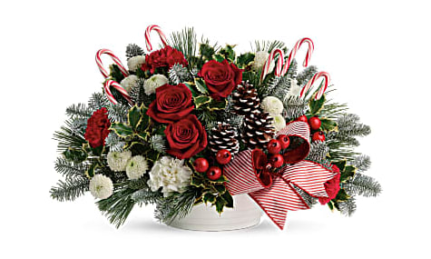 Christmas arrangement with red roses, candy canes, and pinecones in a white container