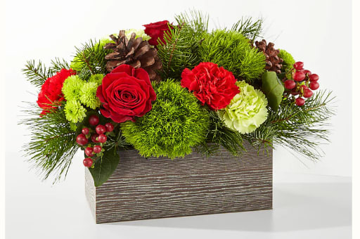 Red roses and carnations in a rectangular wooden box with pinecones