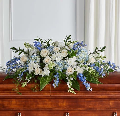 White and blue floral arrangement on a wooden casket