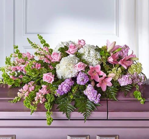 Pink and white floral casket spray with lilies, roses, and hydrangeas
