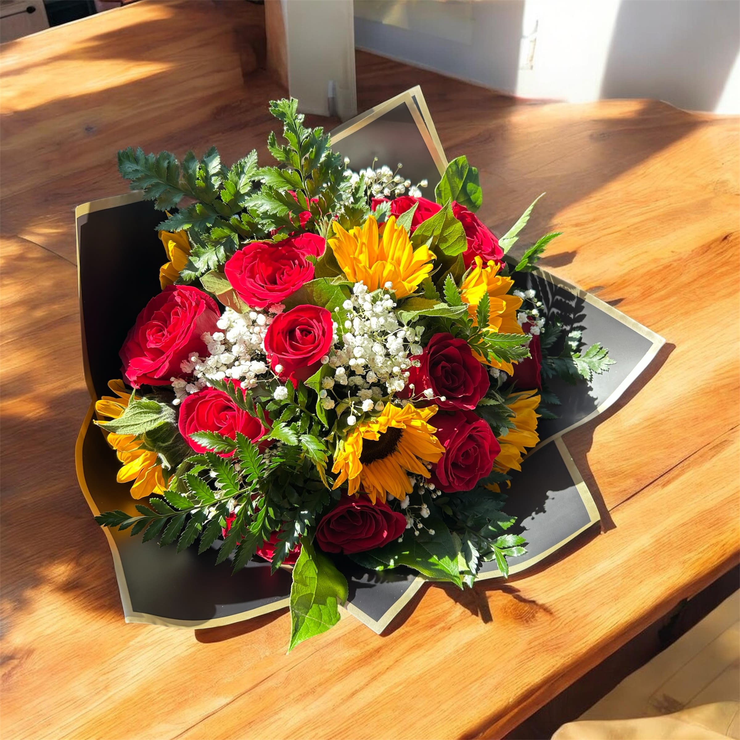 Bouquet of red roses and yellow sunflowers wrapped in black paper