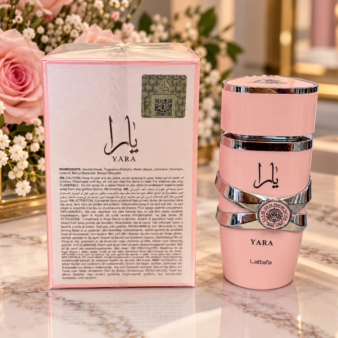 Pink perfume bottle and matching box beside pink roses