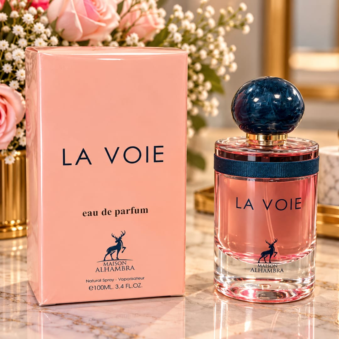 Pink perfume box and bottle on a marble surface with flowers behind