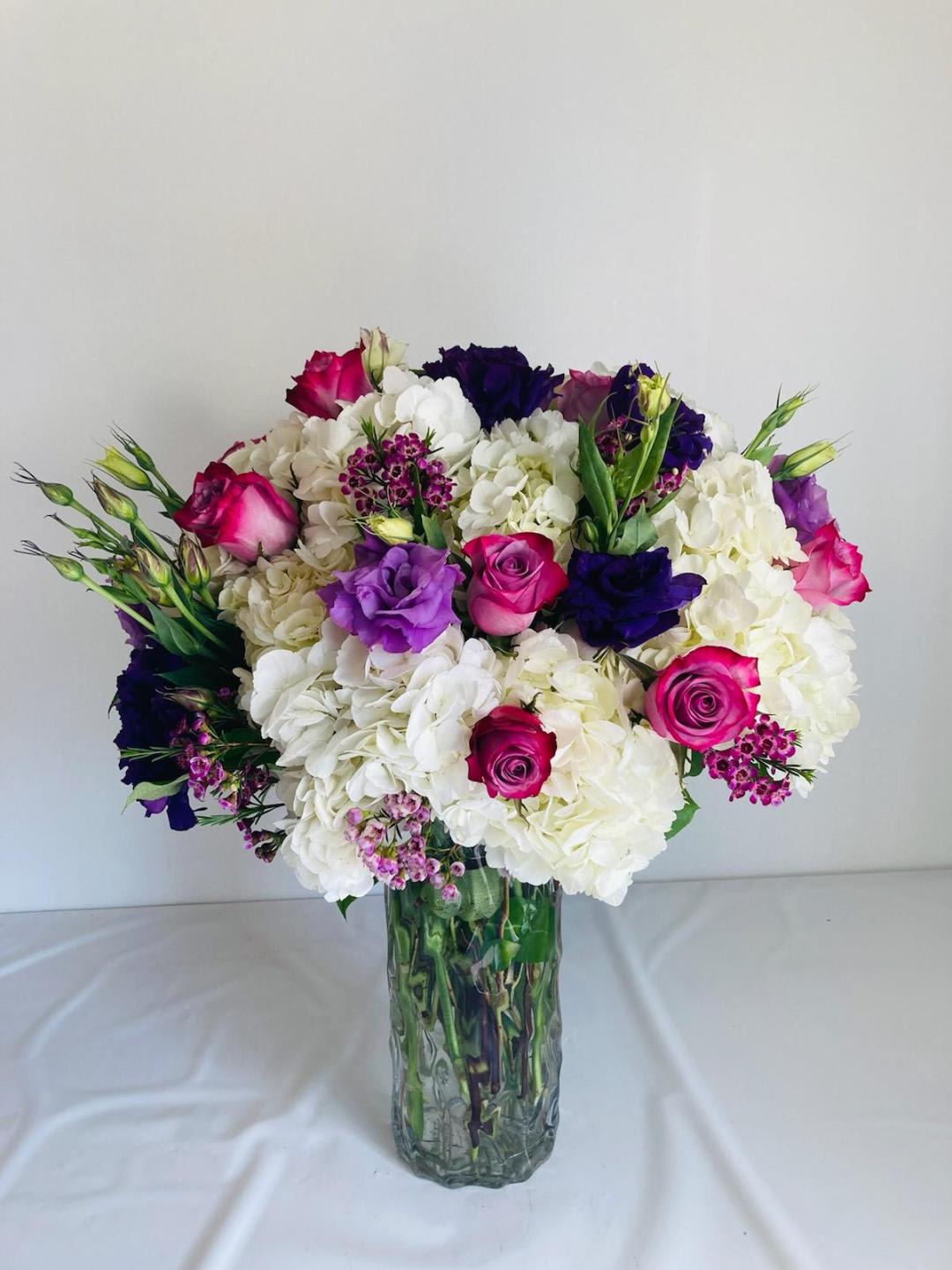 Bouquet of white hydrangeas and pink and purple roses in a glass vase