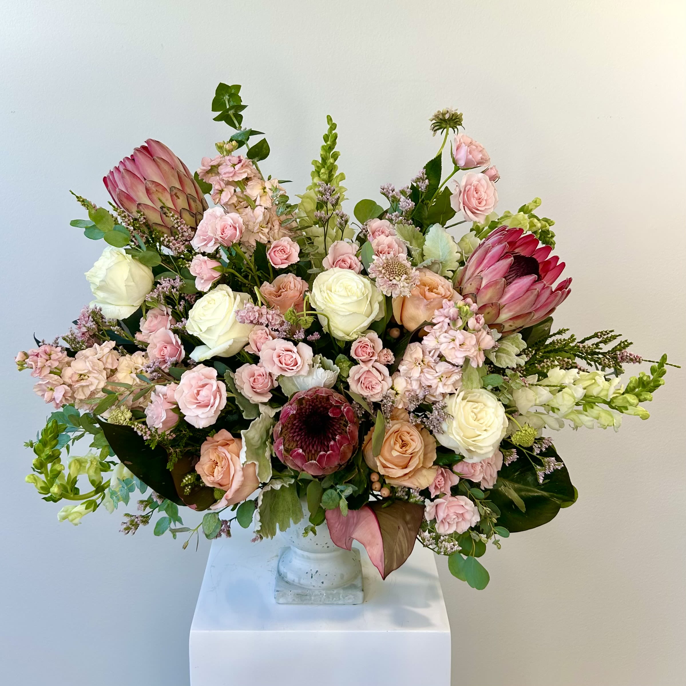 Large pastel bouquet with roses and protea in a white vase
