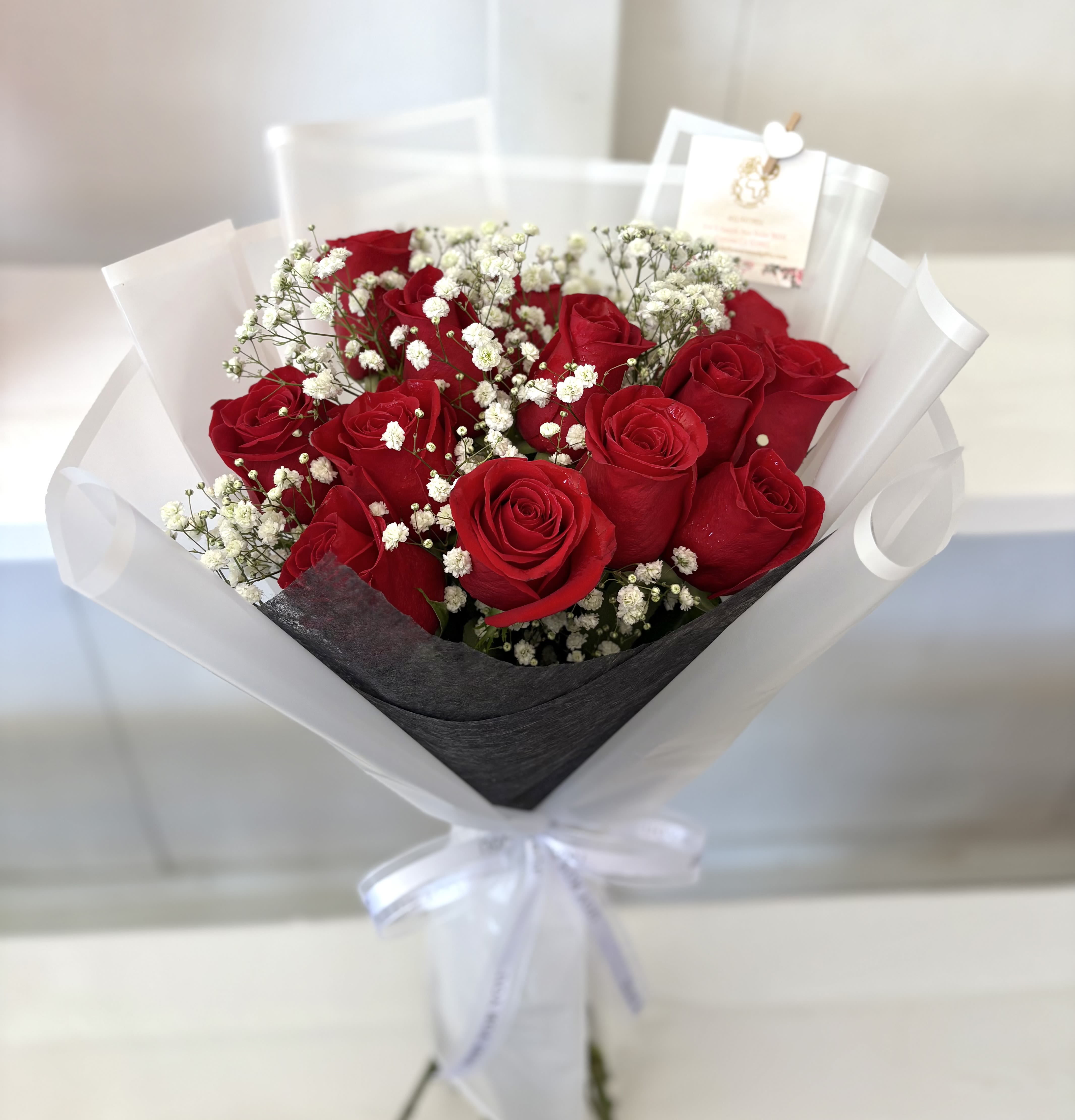 Bouquet of red roses with white baby's breath in white wrap