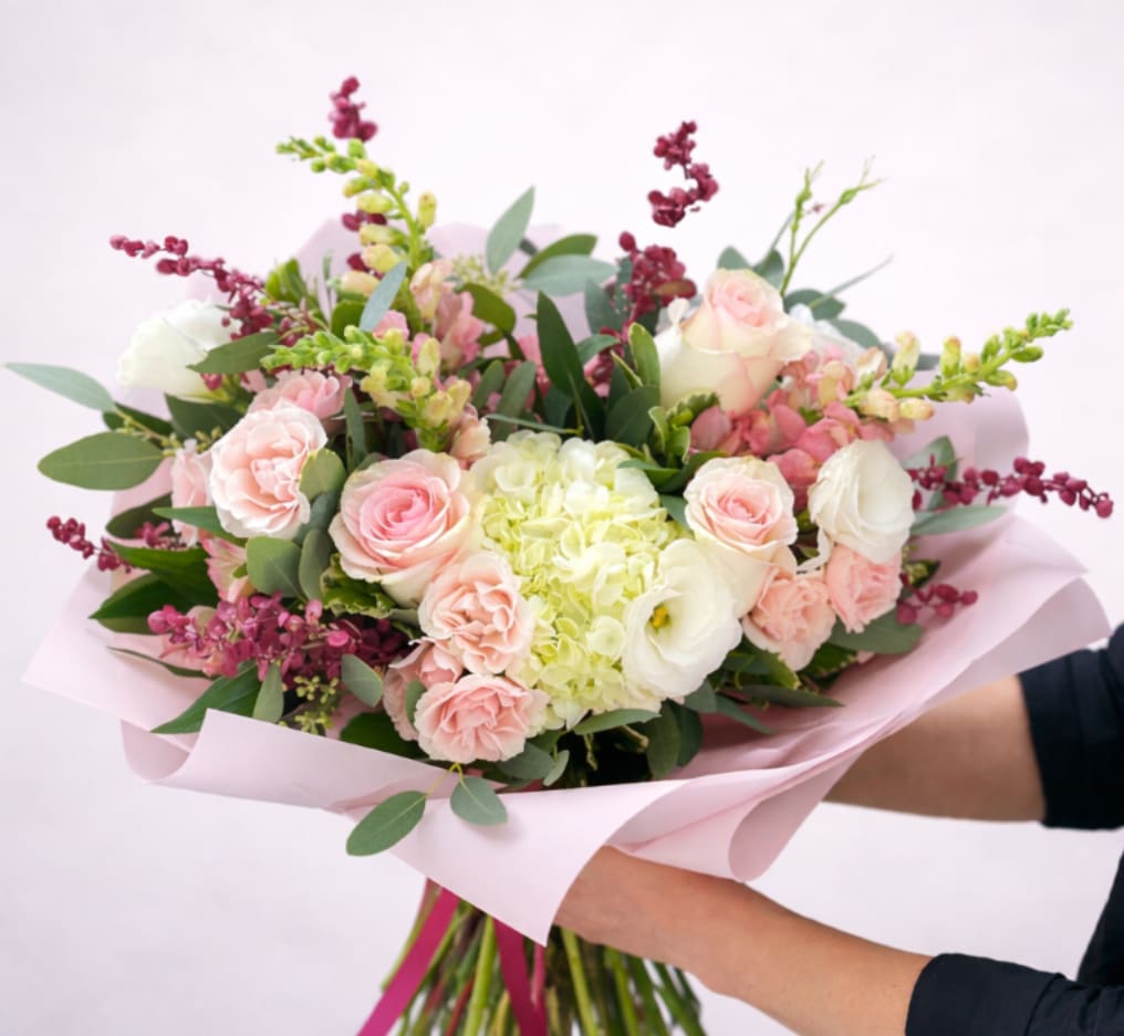 Heart On Your Sleeve Handtied Bouquet - A delicate romantic handtied bouquet with soft white and blush hues and accents of burgundy. This classy bouquet includes mondial roses, tender white lisianthus, elegant snapdragons, garden spray roses, and premium hydrangea. It's the perfect wingman on a third date or a must-have for your wedding anniversary.   Please note that this does not come with a vase.