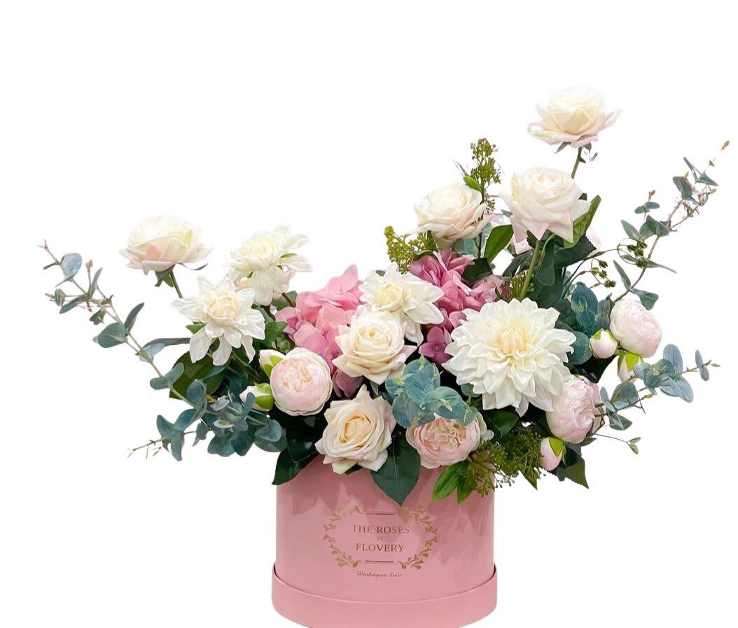 Pink and white floral arrangement in a pink round box
