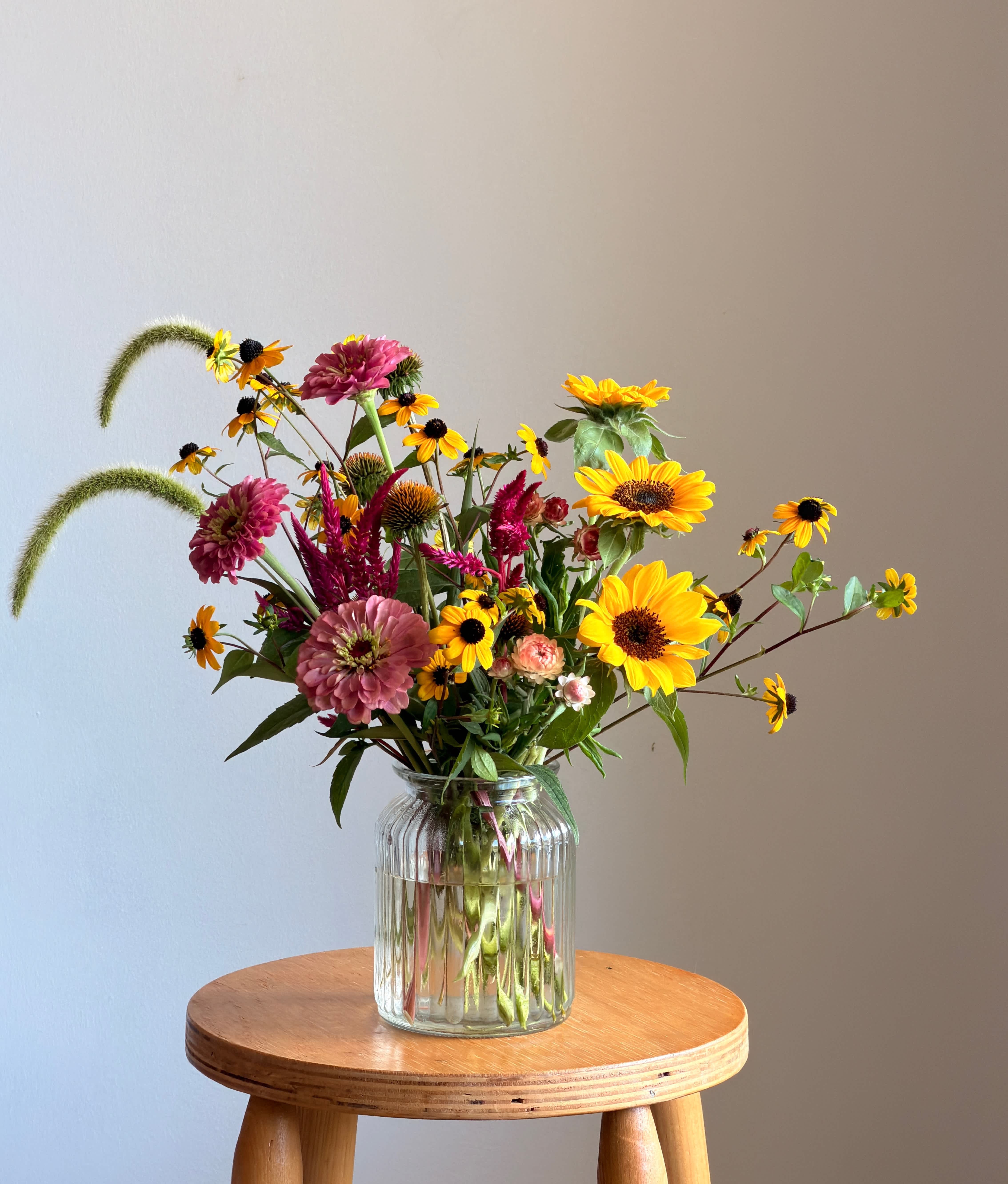Mixed bouquet of yellow and pink flowers in a clear glass vase