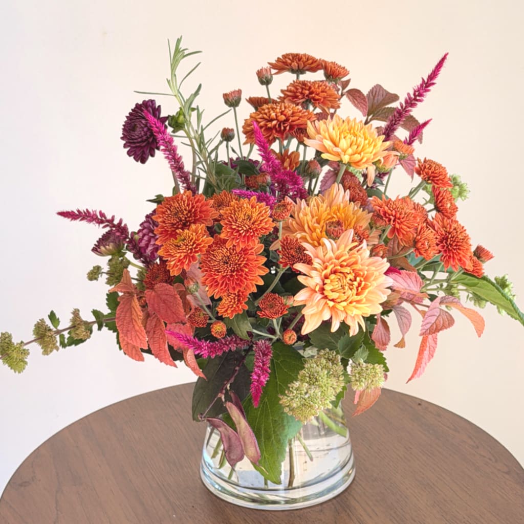 Orange and pink chrysanthemum bouquet in a clear glass vase