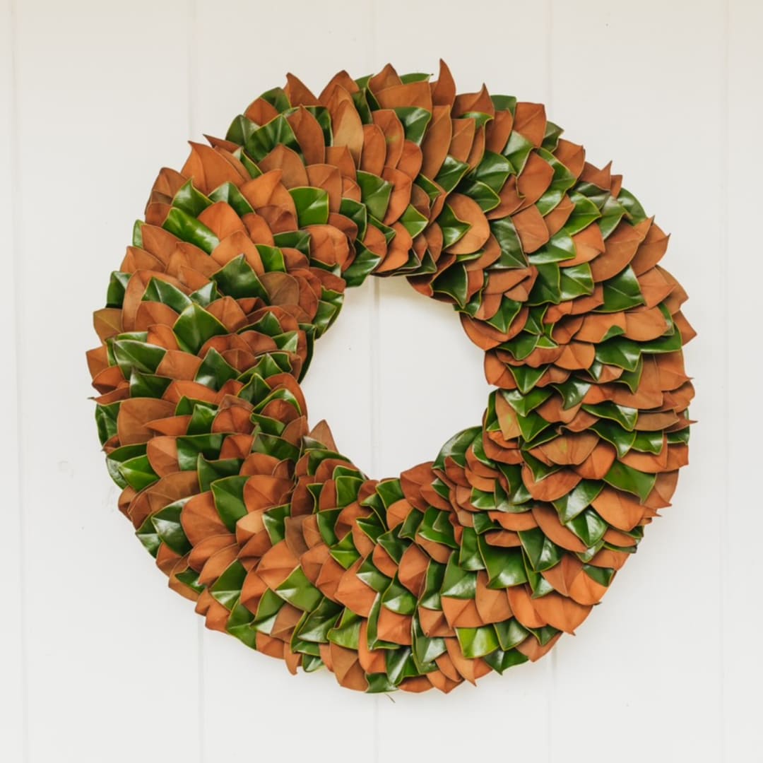 Round wreath of orange and green leaves on a white door
