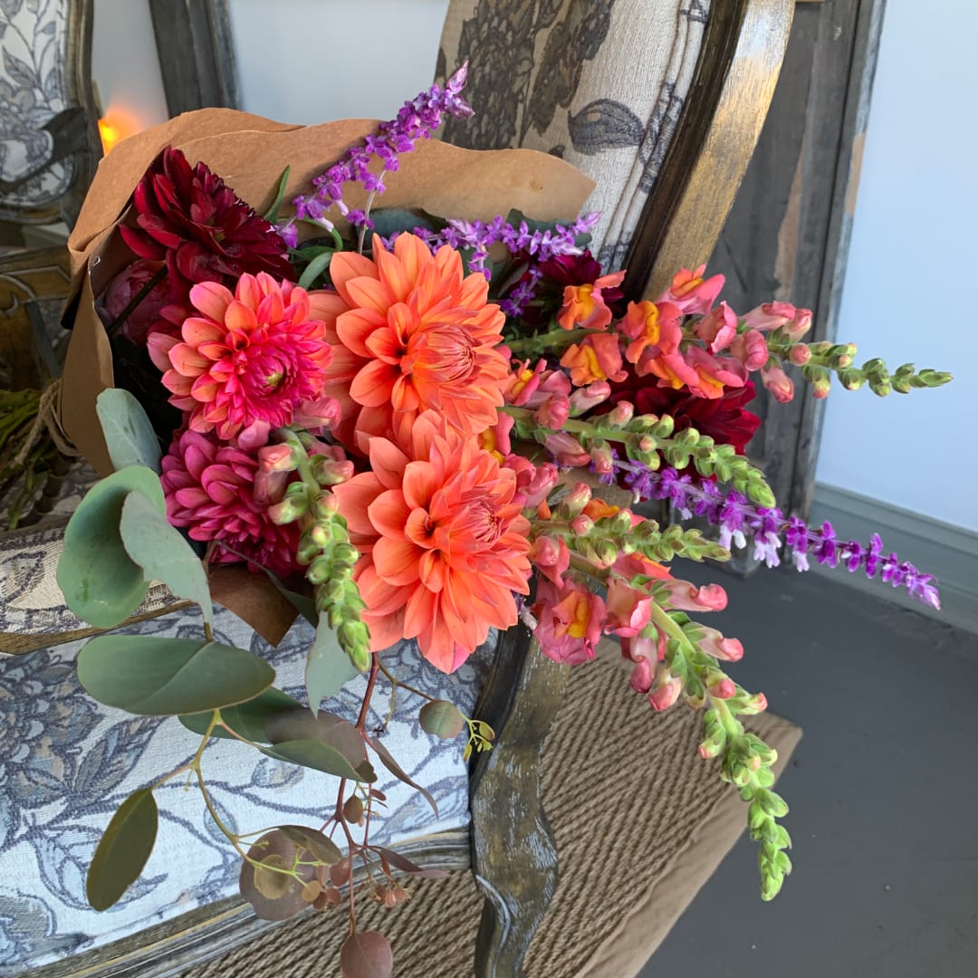 Bouquet of orange, pink, and purple flowers wrapped in brown paper