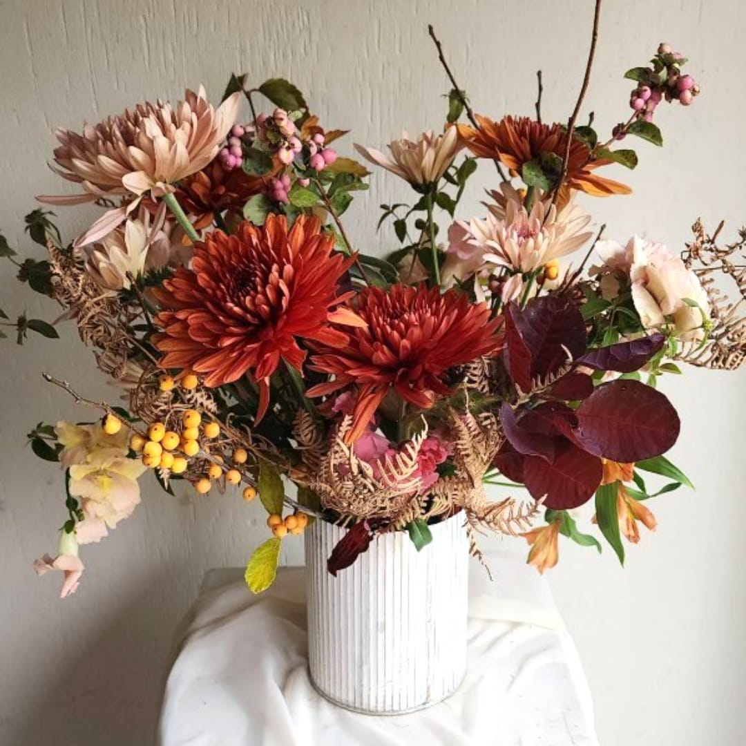 Autumn bouquet of orange and blush chrysanthemums in a white vase