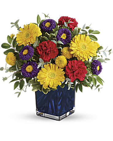 Teleflora's Pretty Perfect Bouquet - Color outside the lines with the bright, beautiful hues of this pretty perfect bouquet! Presented in a cobalt cube, this gift of sunny yellow gerberas with red carnations and purple asters is a bold statement of love and friendship. Yellow gerberas, red carnations, purple matsumoto asters, and yellow button spray chrysanthemums are arranged with huckleberry, variegated pittosporum, and parvifolia eucalyptus. Delivered in a blue cube.
